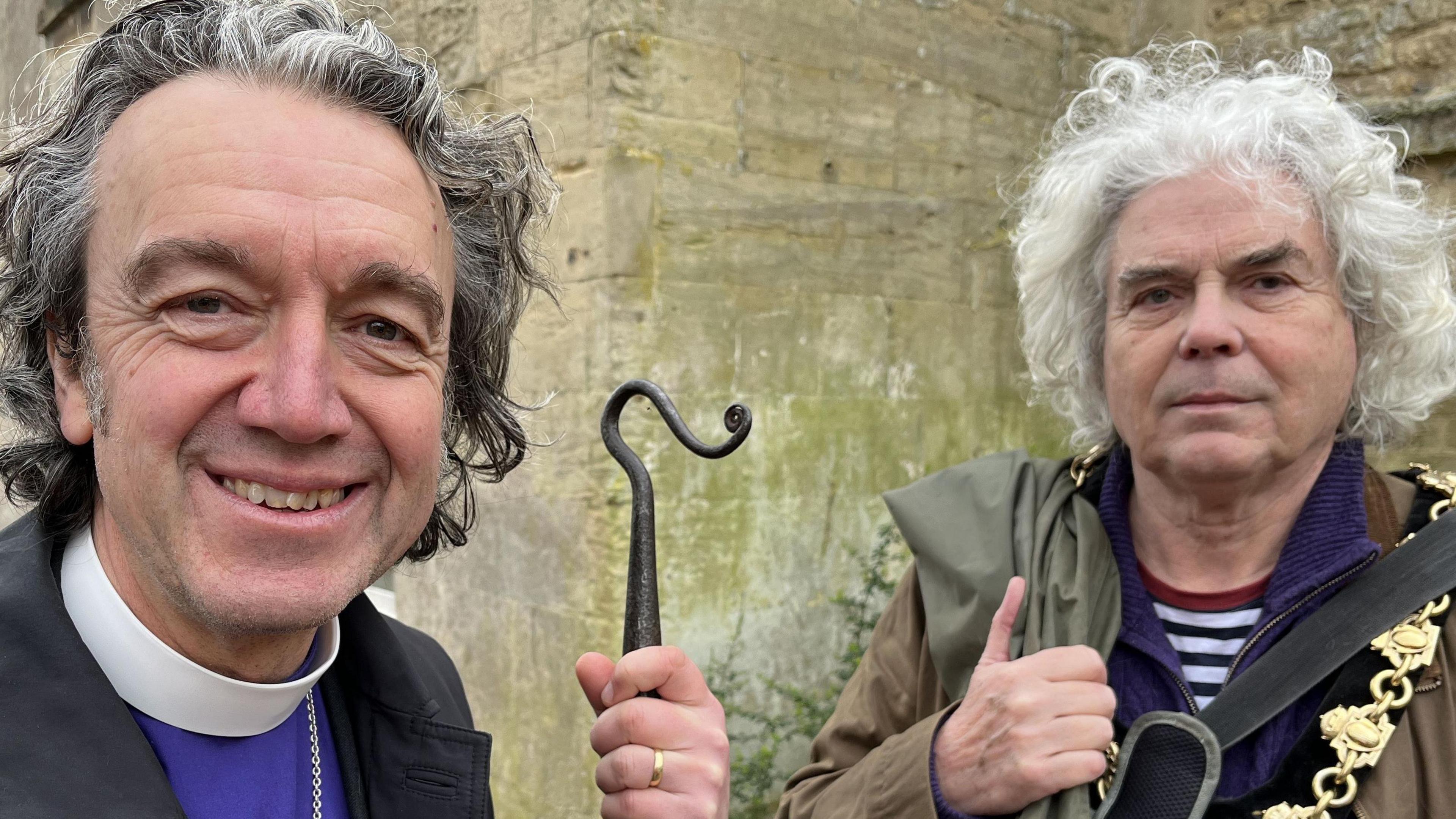 The Bishop of Ramsbury, Andrew Rumsey, smiling and stood next to the Mayor of Calne, Robery MacNaughton who is wearing is Mayoral chain and has waders hanging over his shoulder