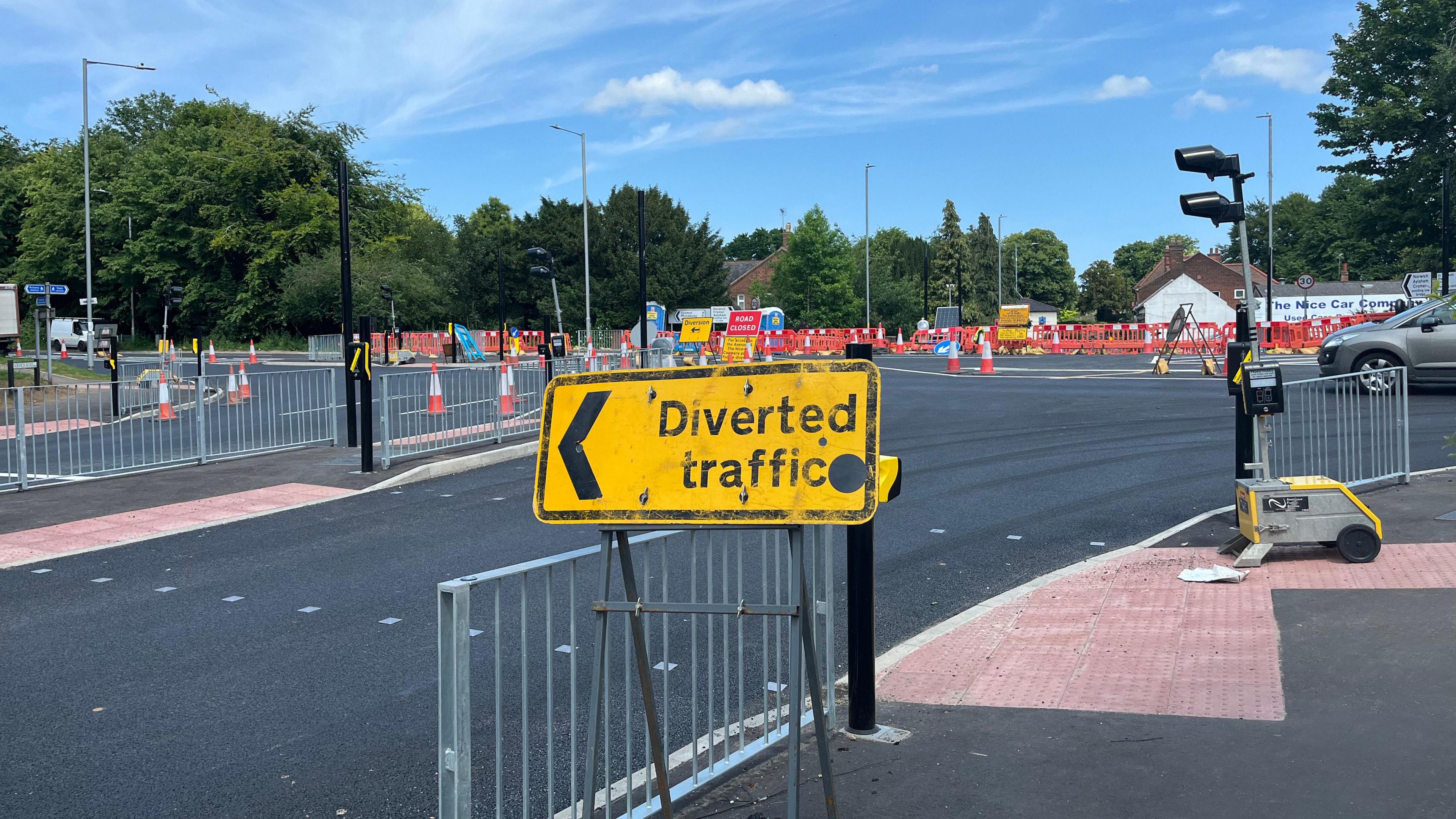 View of the junction into North Walsham which is covered in orange cones, traffic barriers, temporary traffic lights and diversion signs.