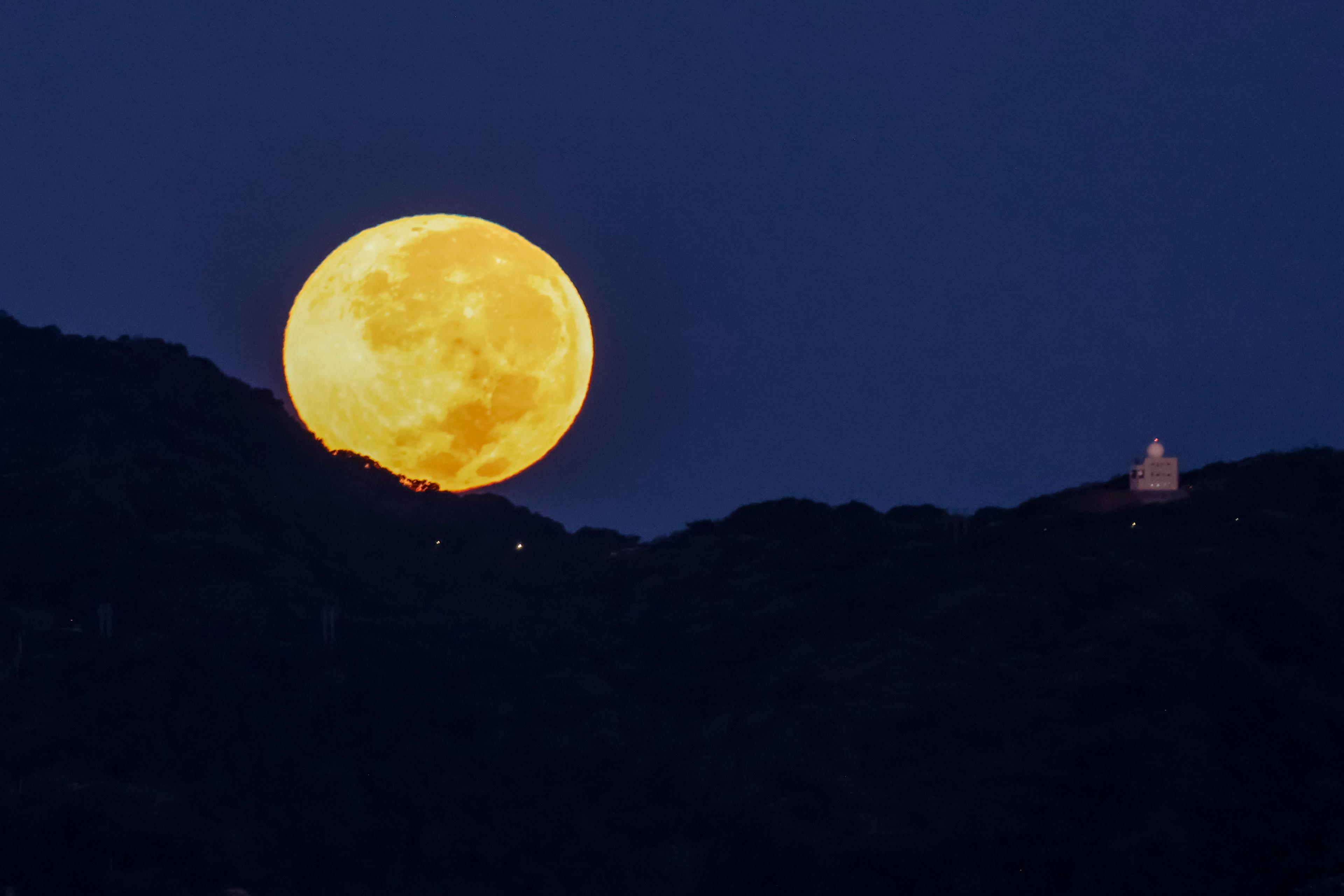 A yellow supermoon appears to be rolling down the hillside in Taipei, Taiwan