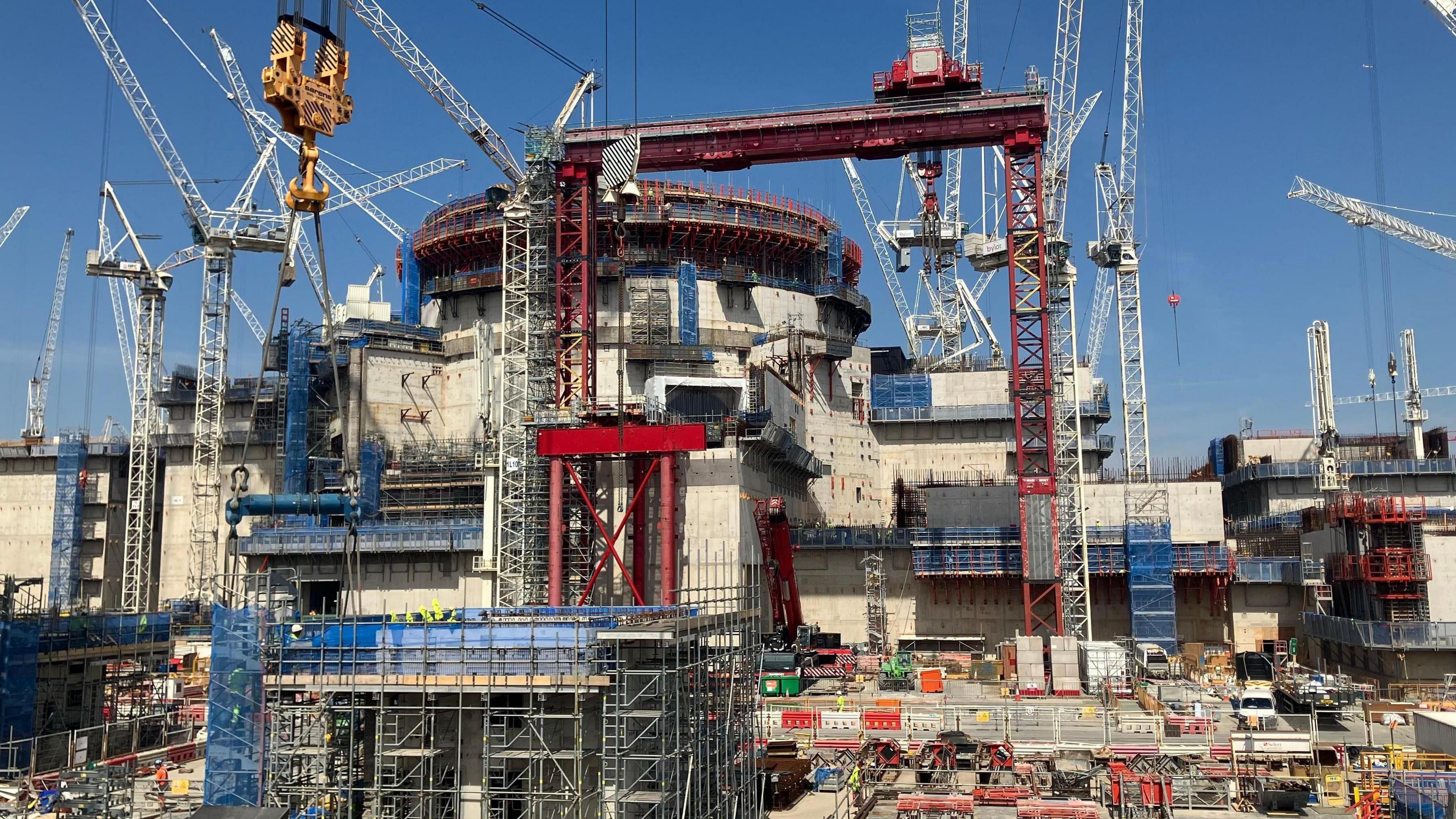 Building work at Hinkley Point C nuclear power station.  Several cranes and scaffolding surround the construction of a building.  