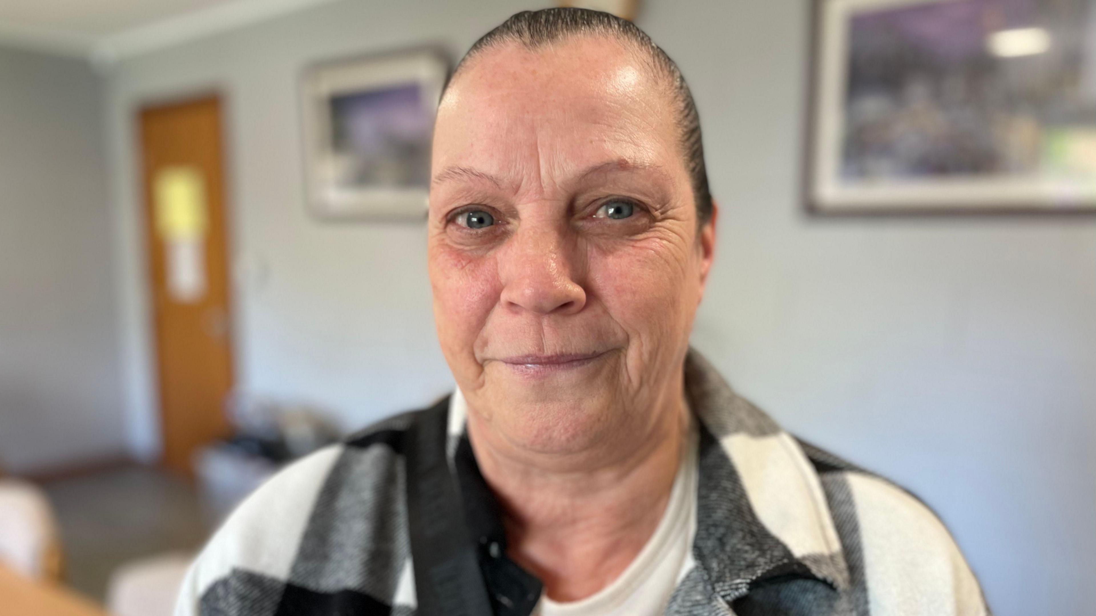 Ann Wright has black hair that is tied up. She is wearing a black and white check shirt.