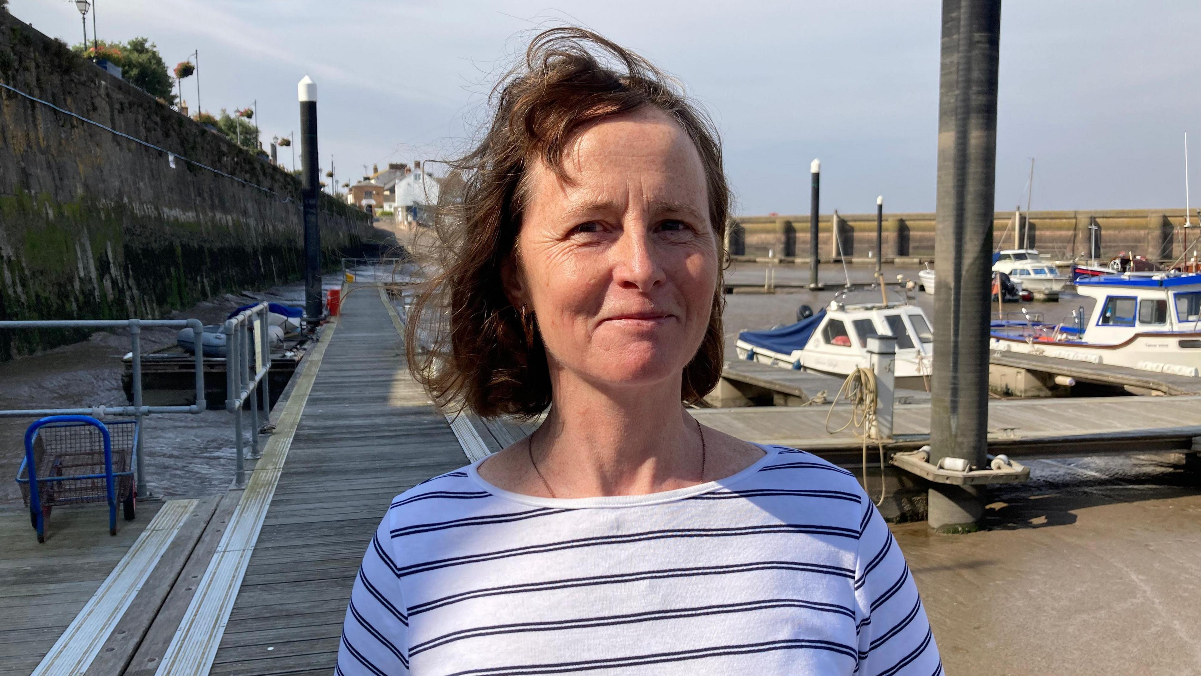 Kate Jeffreys in a black and white striped top smiling and standing at the marina