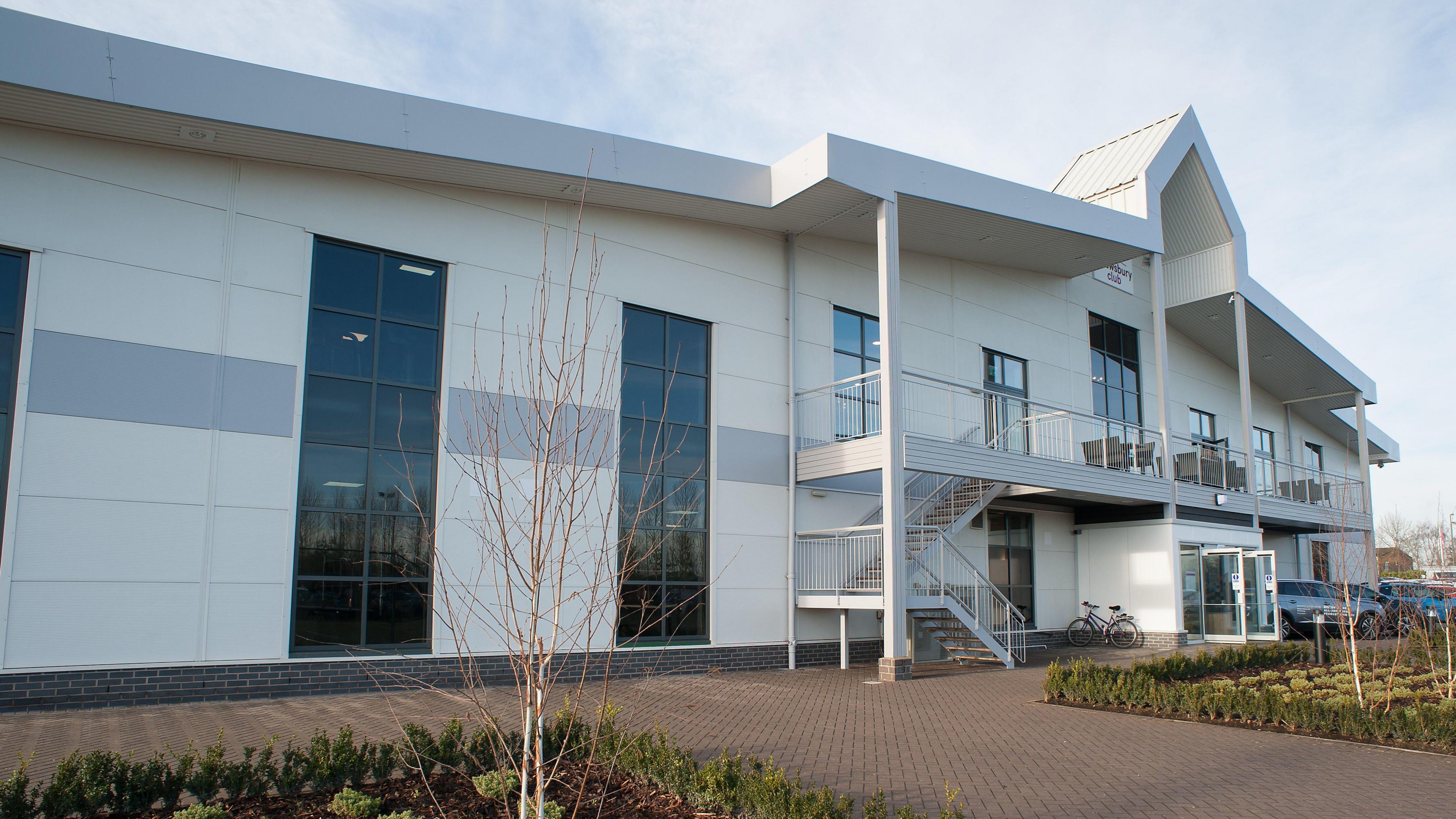 The front of a fitness club. It is white with large windows. There is a sign that says "Shrewsbury Club".