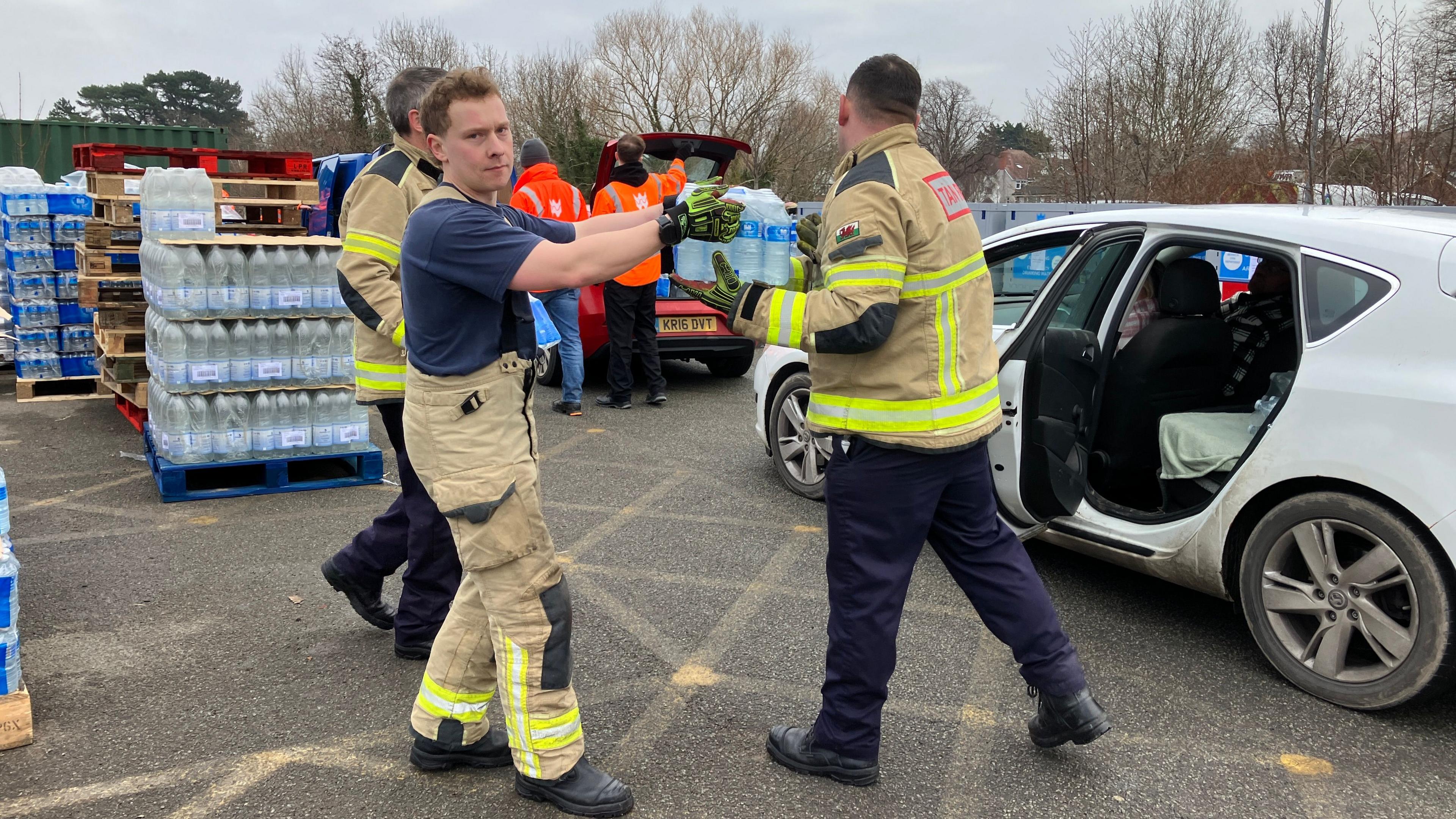 Fire fighters lend a hand putting water supplies into cars of those in need at Eirias Park on Sunday.