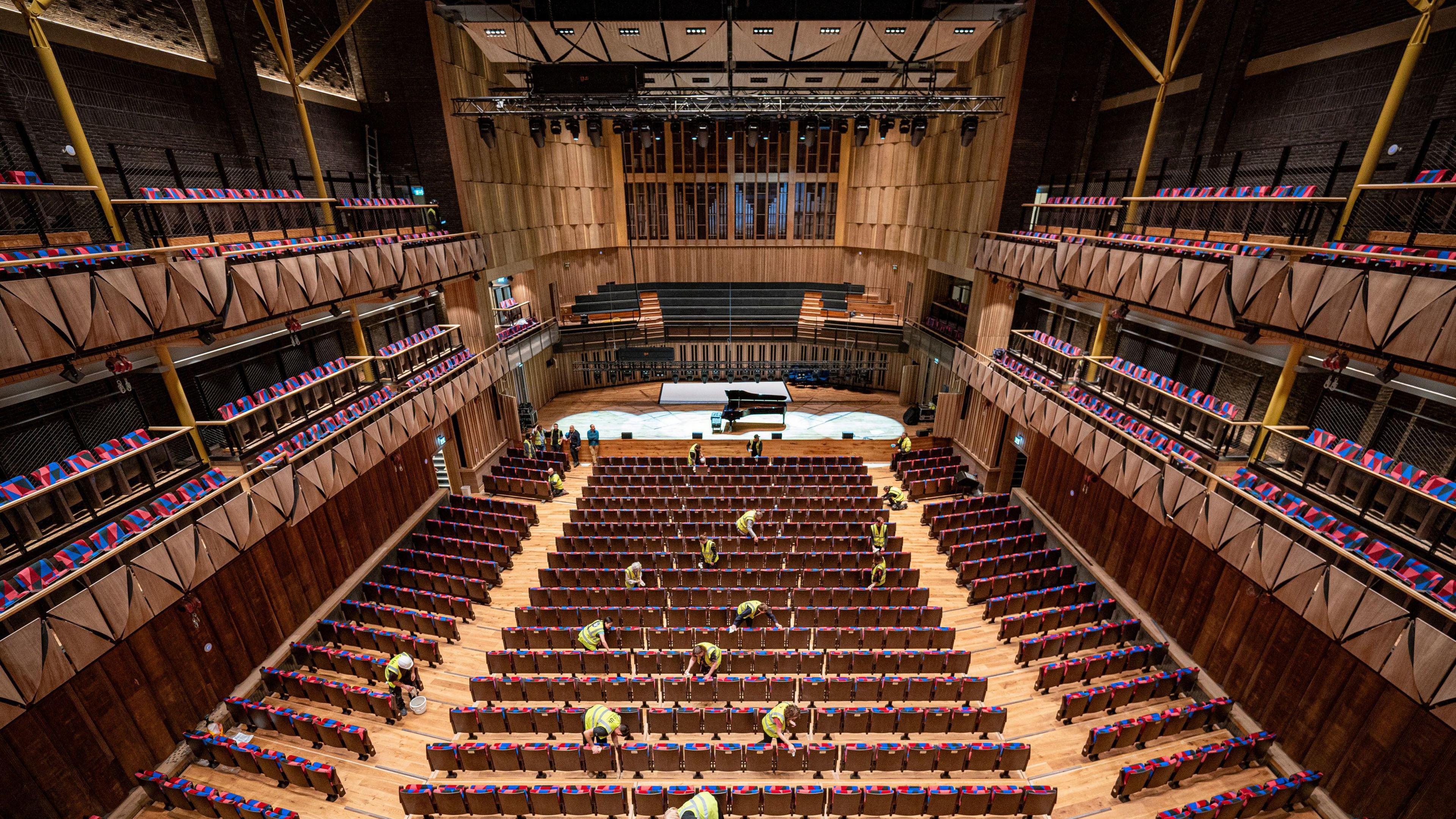 A picture of the inside of Bristol Beacon, with contractors cleaning the seats inside the venue ahead of its opening. 