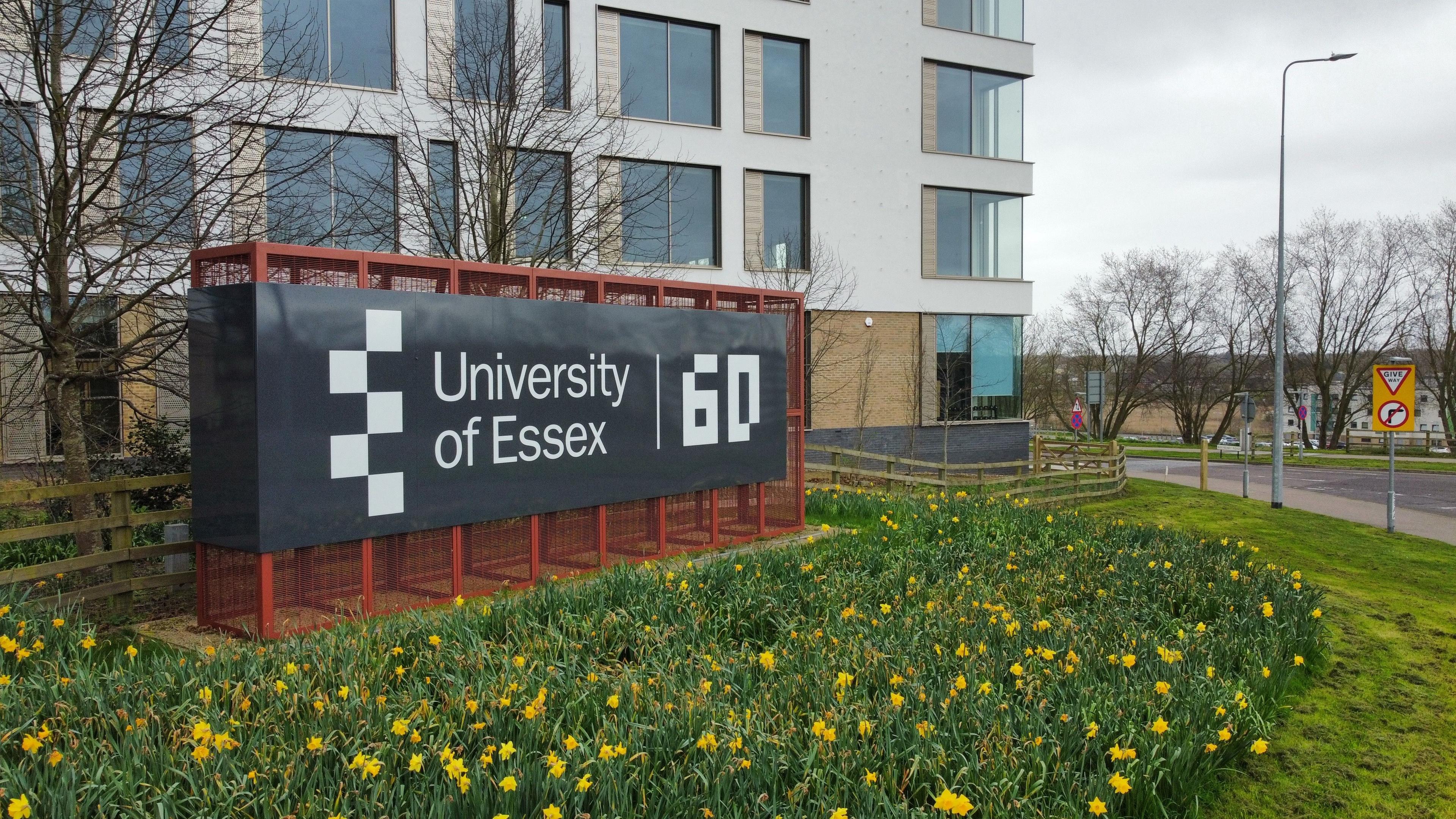 A black sign that reads University of Essex and a building behind 