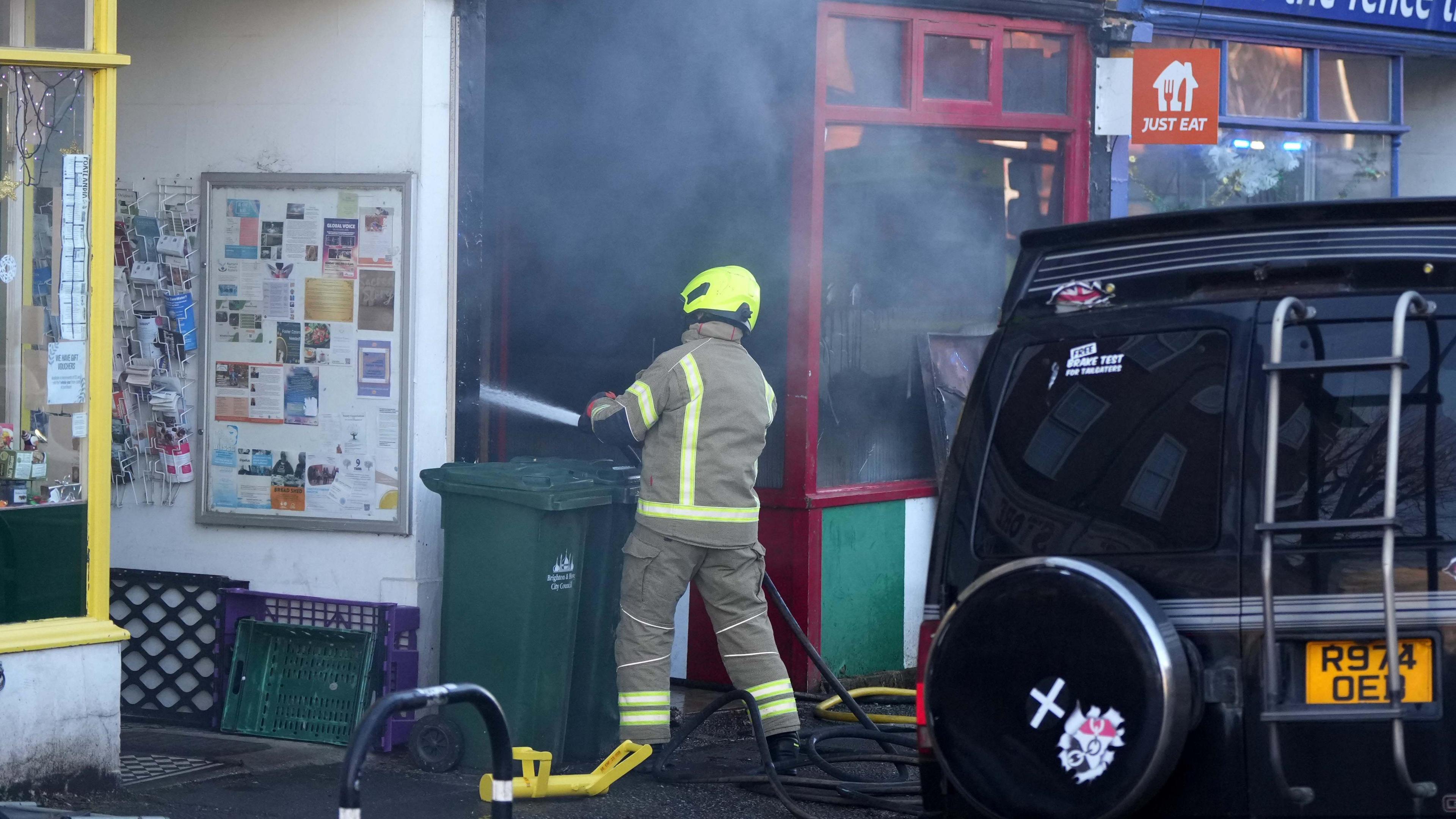 A firefighter sprays water from a hose into a smoking restaurant.