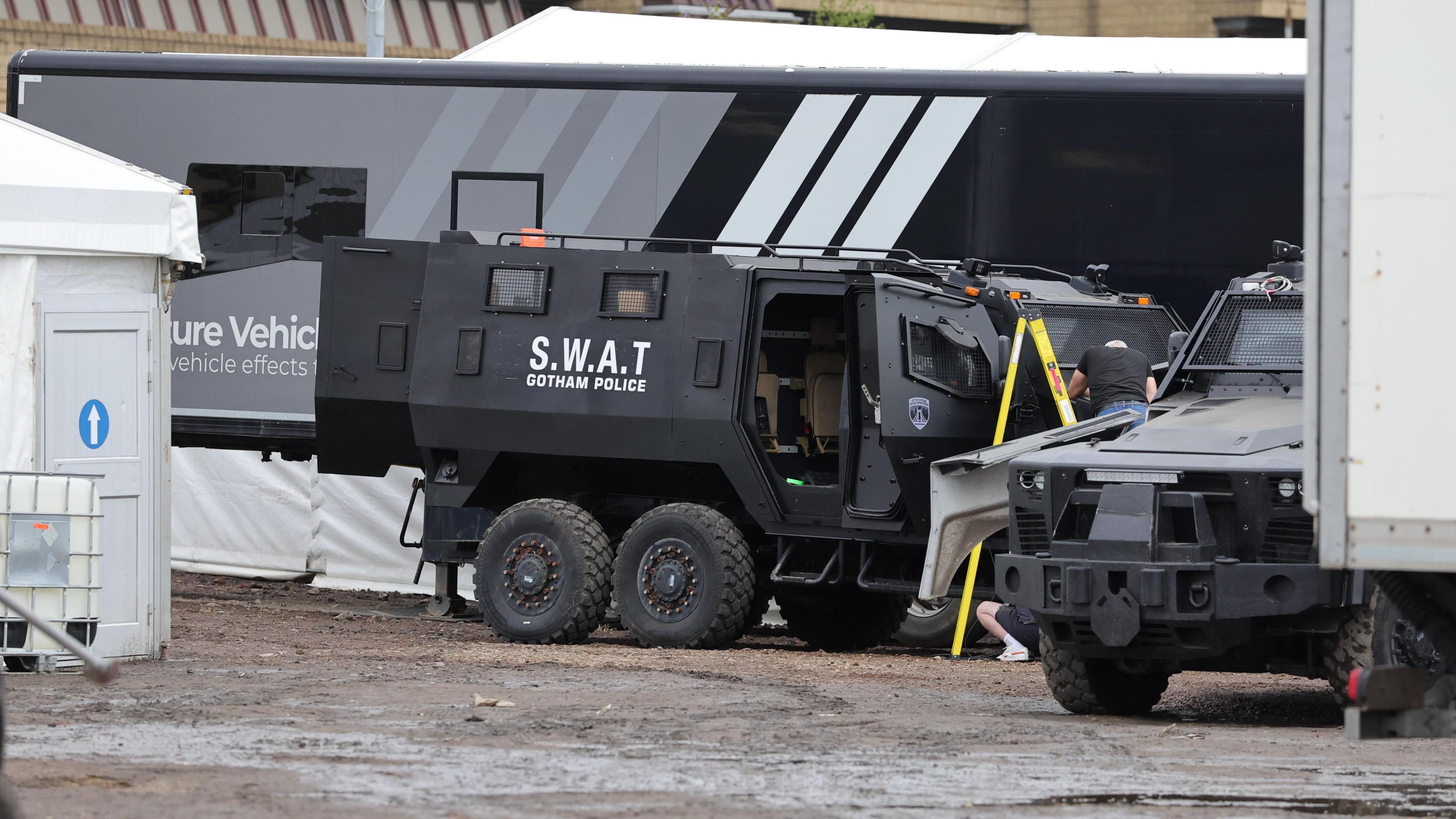 A large black truck, with SWAT - GOTHAM POLICE written in white letters on the side.