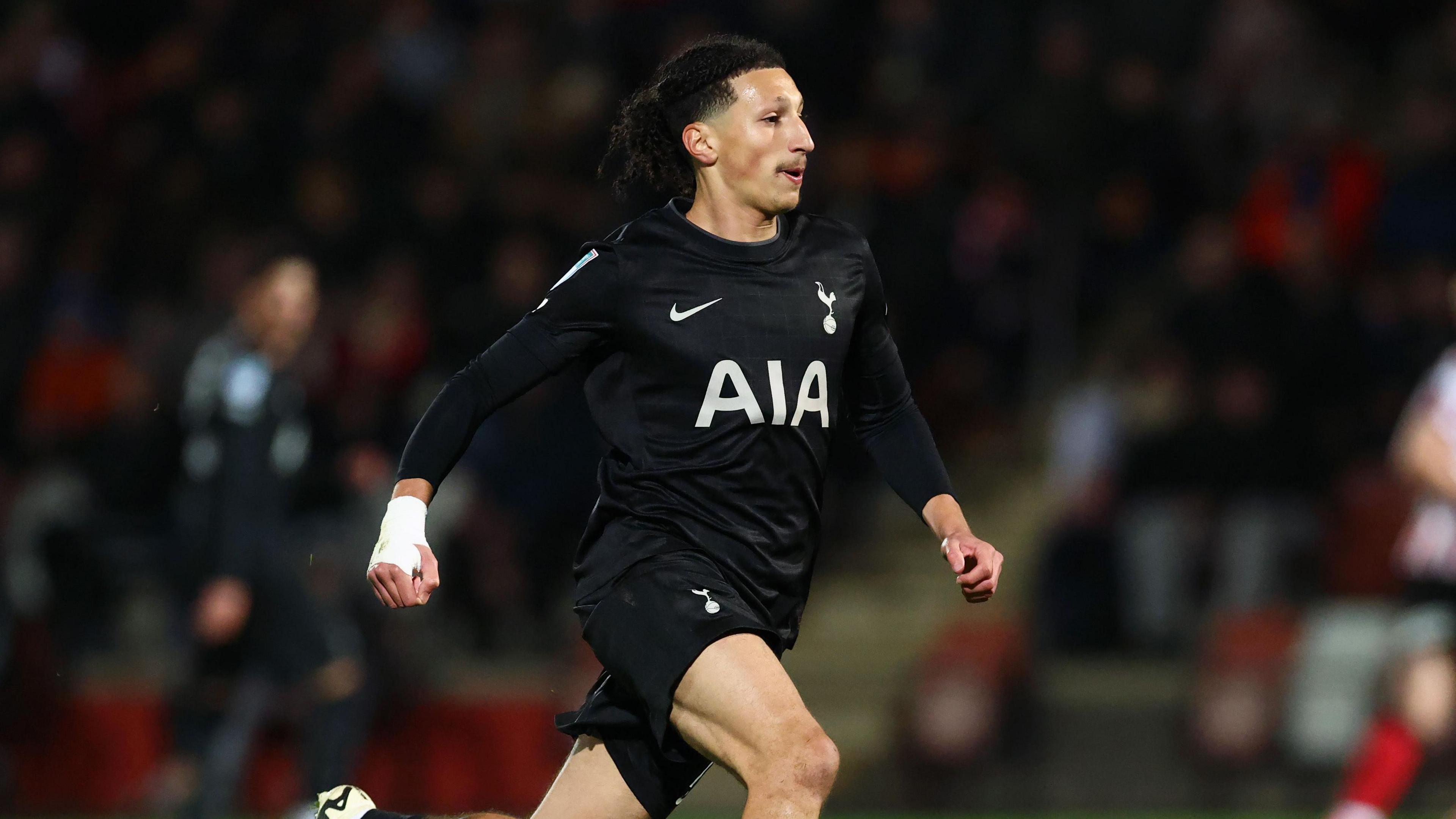 Yusuf Akhamrich in a side profile running on the pitch during a match for Tottenham under-21s