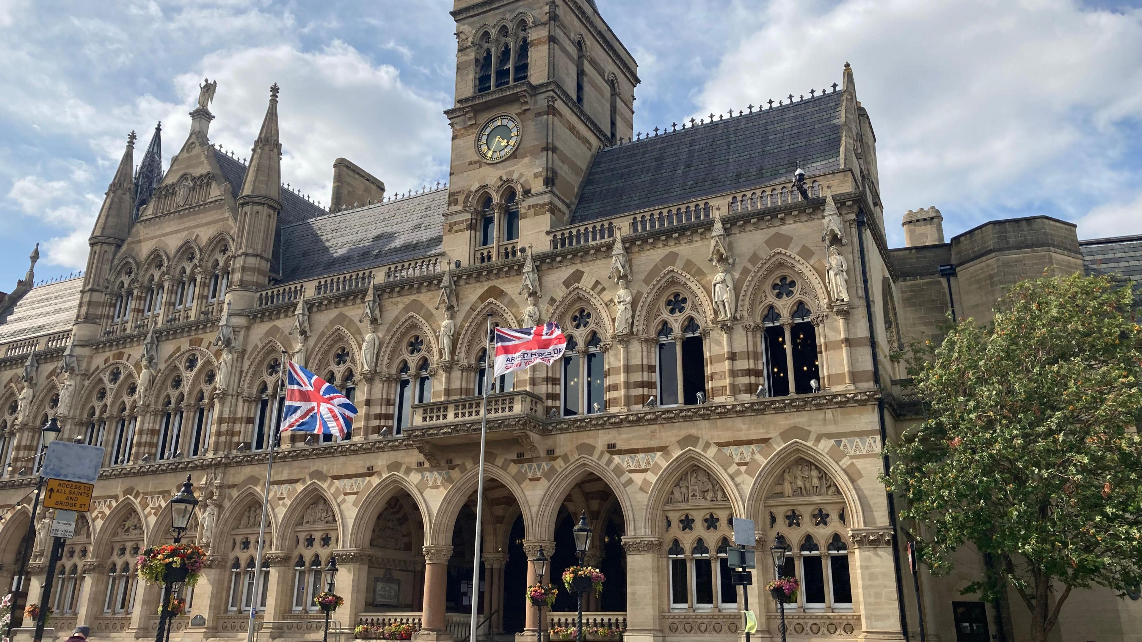 The exterior of Northampton's Guildhall bulding with a union jack and Armed Forces Day flag being flown.