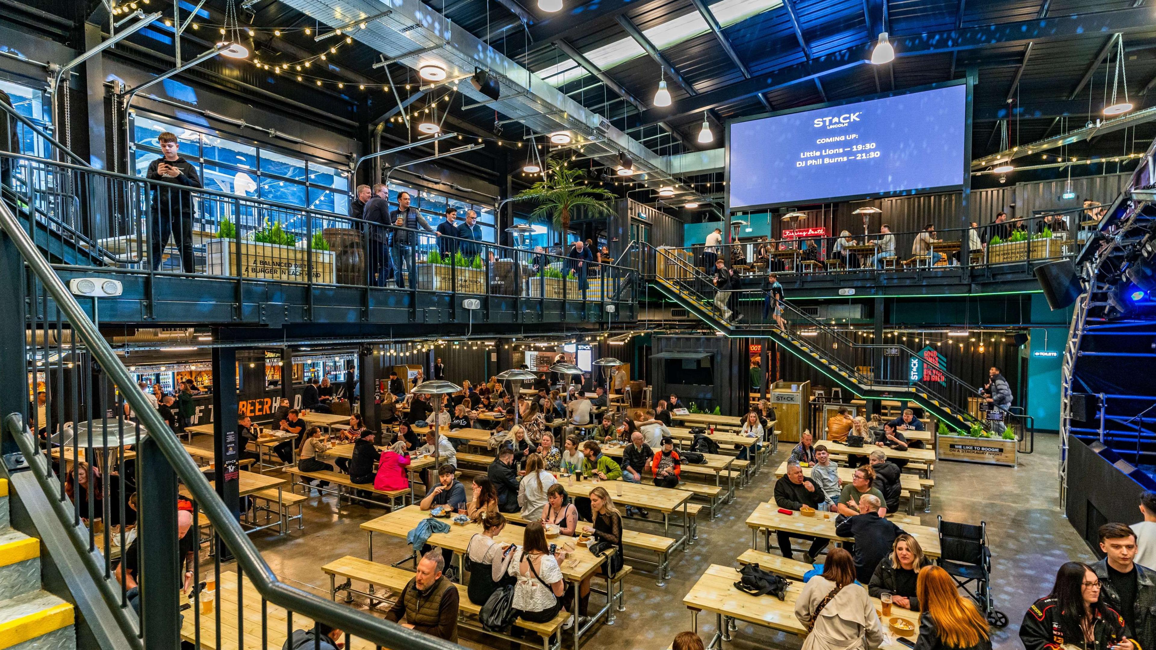 A foodhall with people sitting down at tables, in an open double-floored room. 