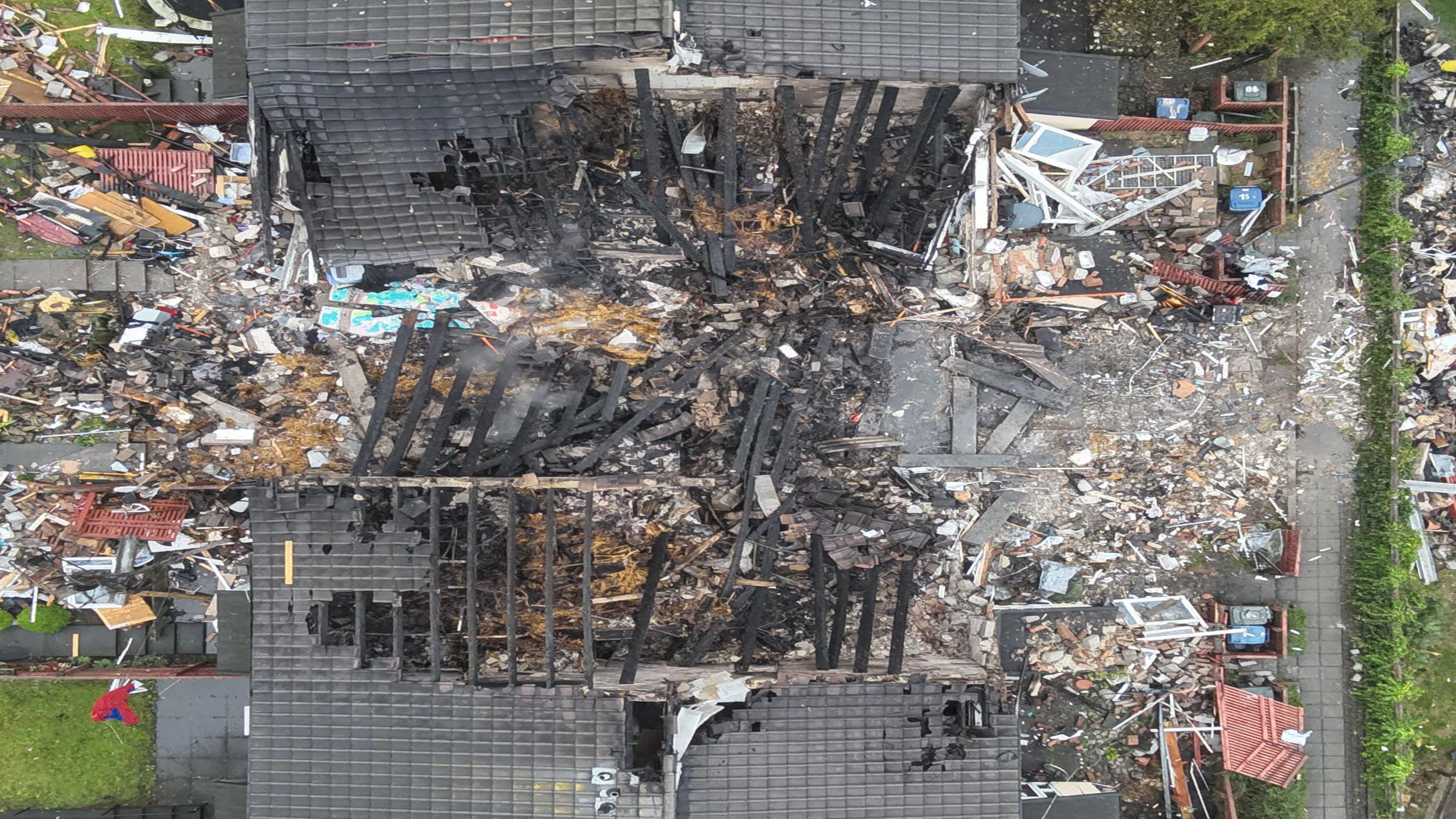 birds eye view of a totally destroyed set of buildings, with rubble and burnt timbers scattered around