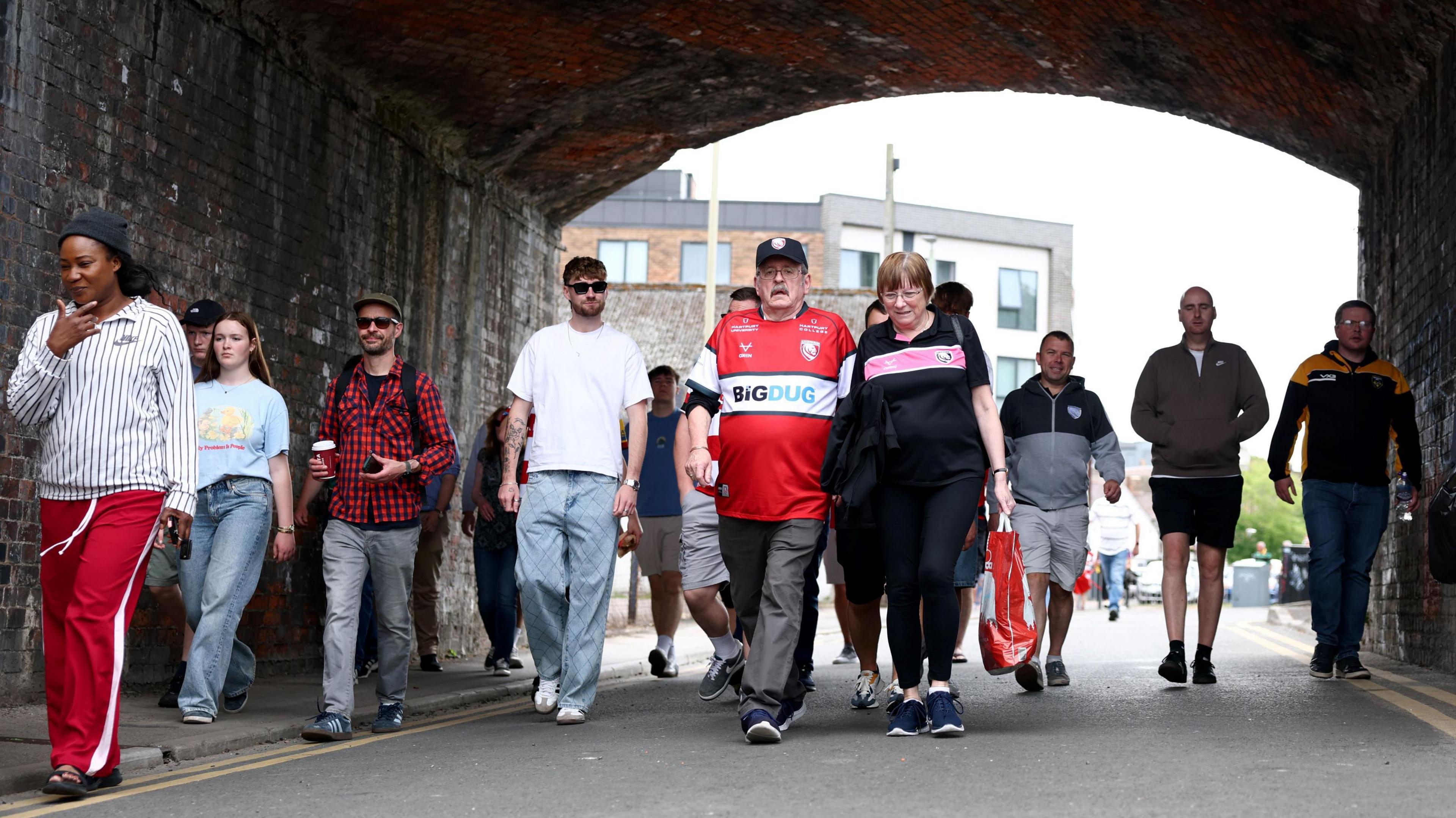 Gloucester Rugby fans walk under an underpass on their way to watch their team at Kingsholm