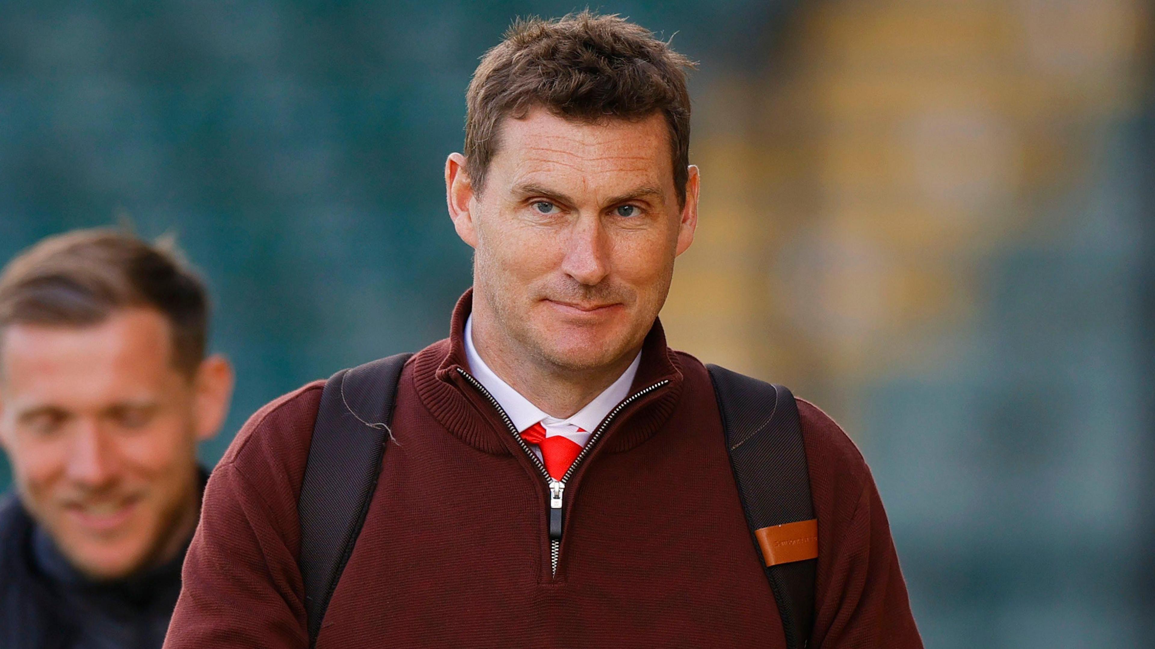 Matt Taylor, wearing a dark red jumper, and smiling.