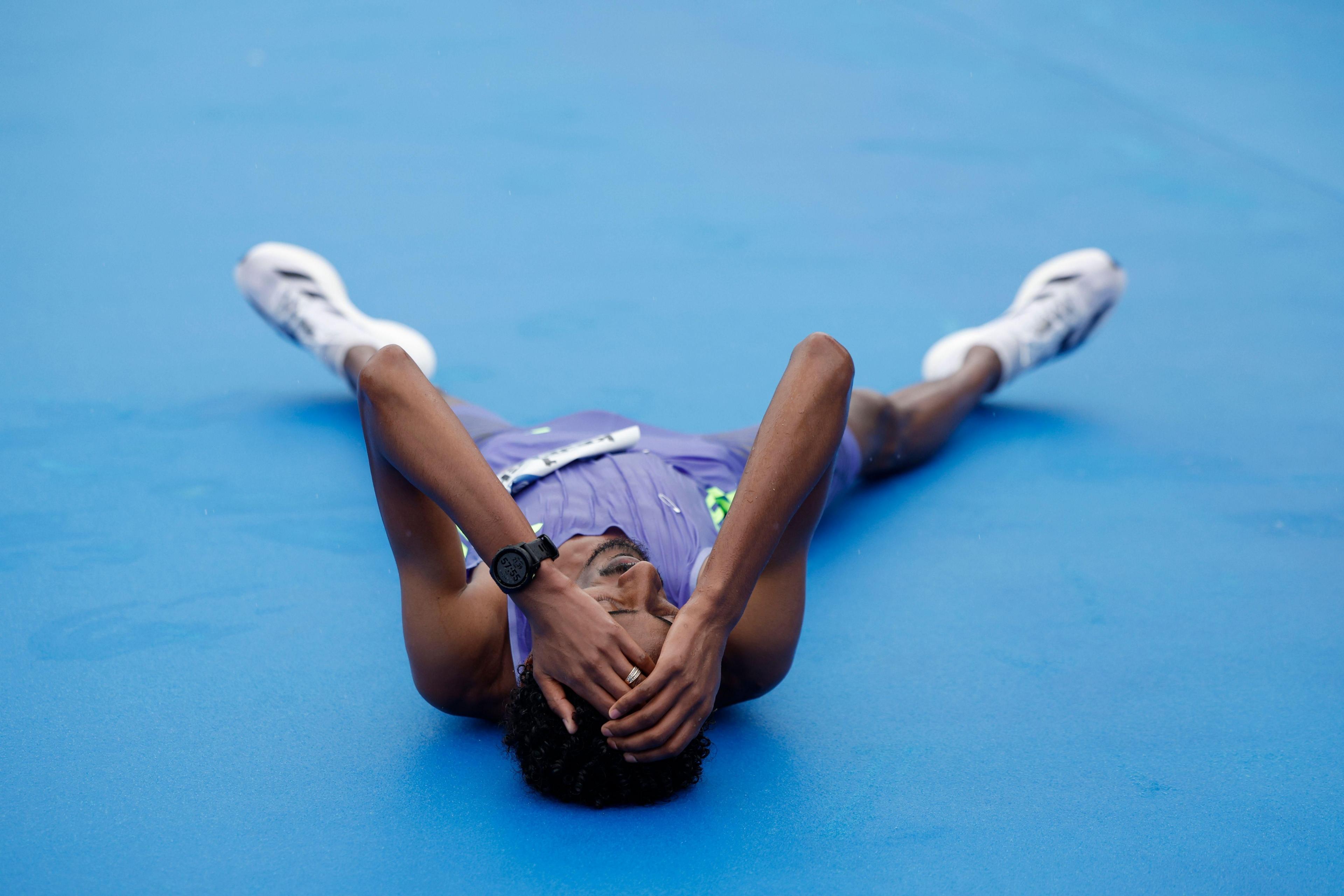 Ethiopian athlete Yomif Kejelcha lays on his back with his legs splayed open after breaking a new world record with a time of 57 minutes and 30 seconds, during the Valencia's Half Marathon held in Valencia.