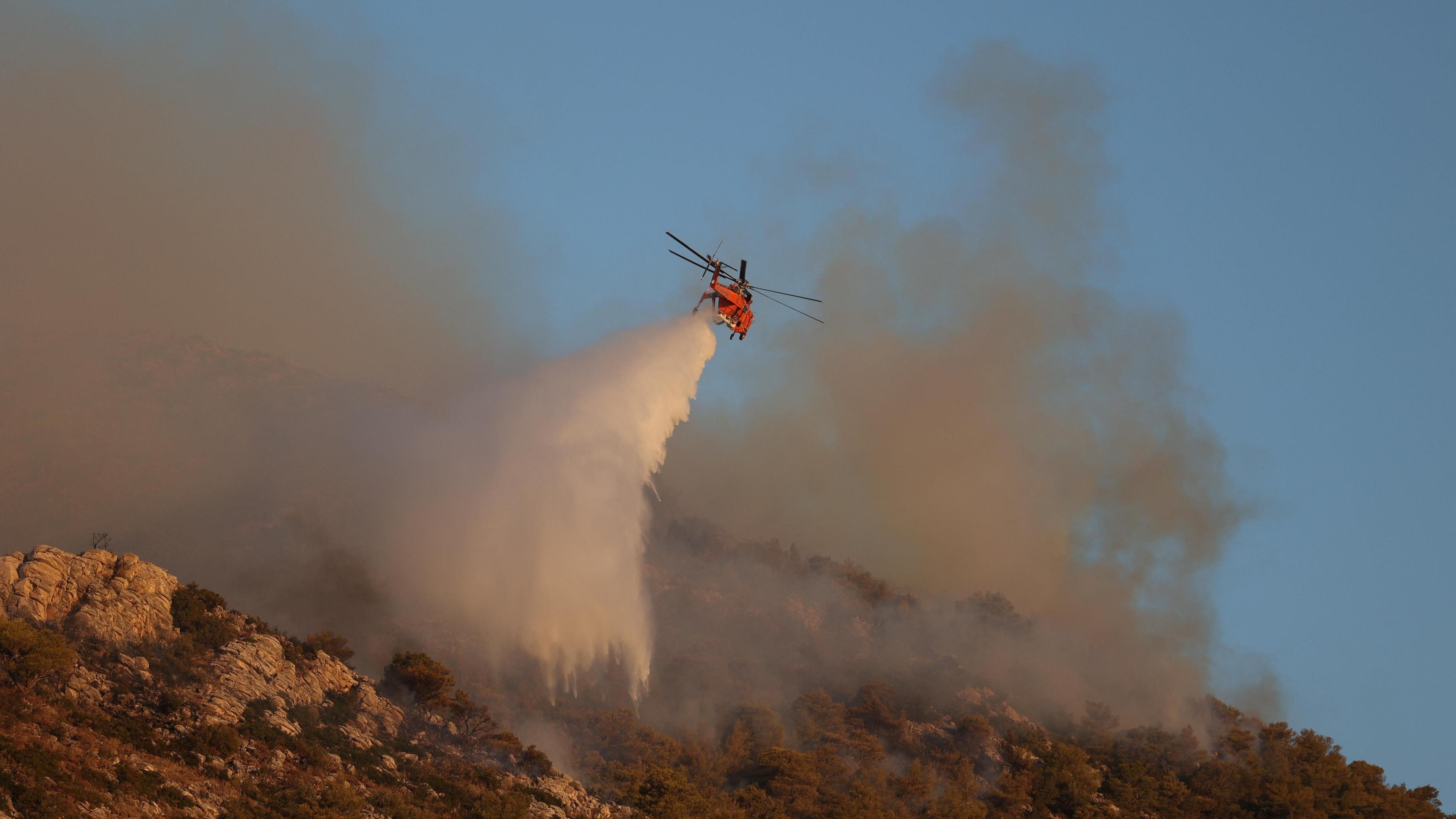 A firefighting helicopter drops water near Nea Makri, east of Athens