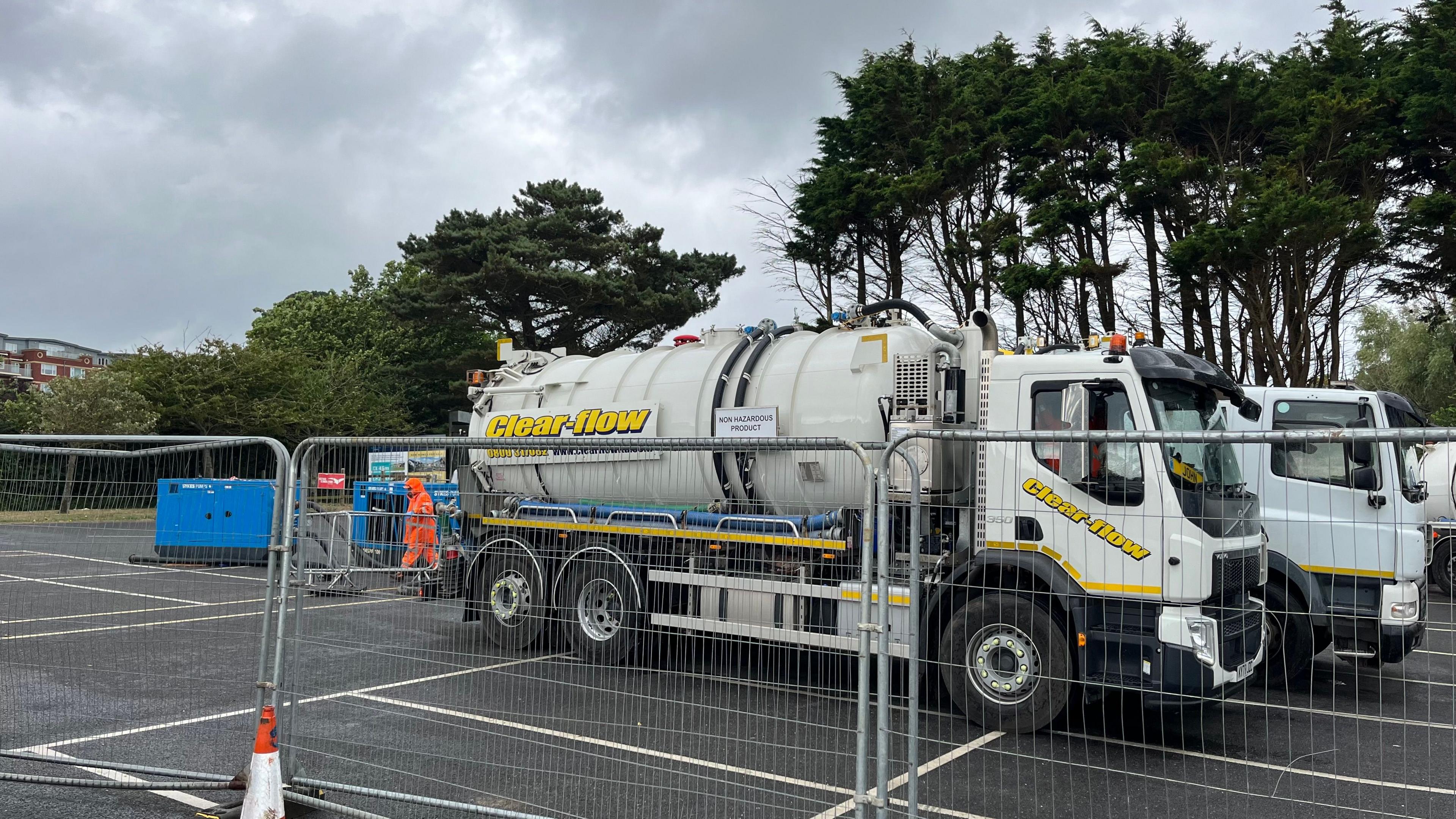 Tankers behind fencing in a car park pumping out sewage in Exmouth