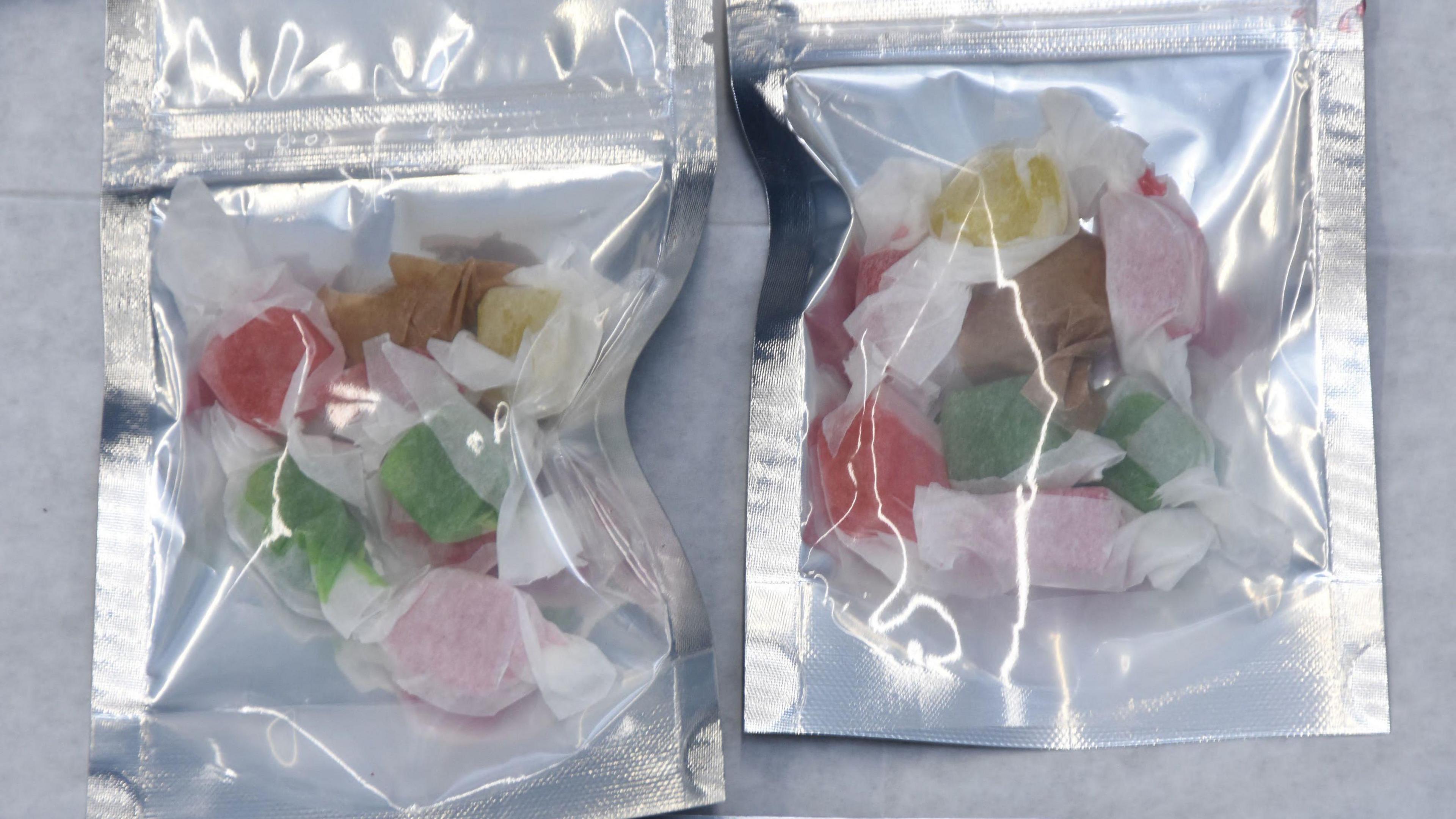 Two silver foil bags with clear fronts, each containing half a dozen or so brightly coloured sweets wrapped in semi-translucent paper