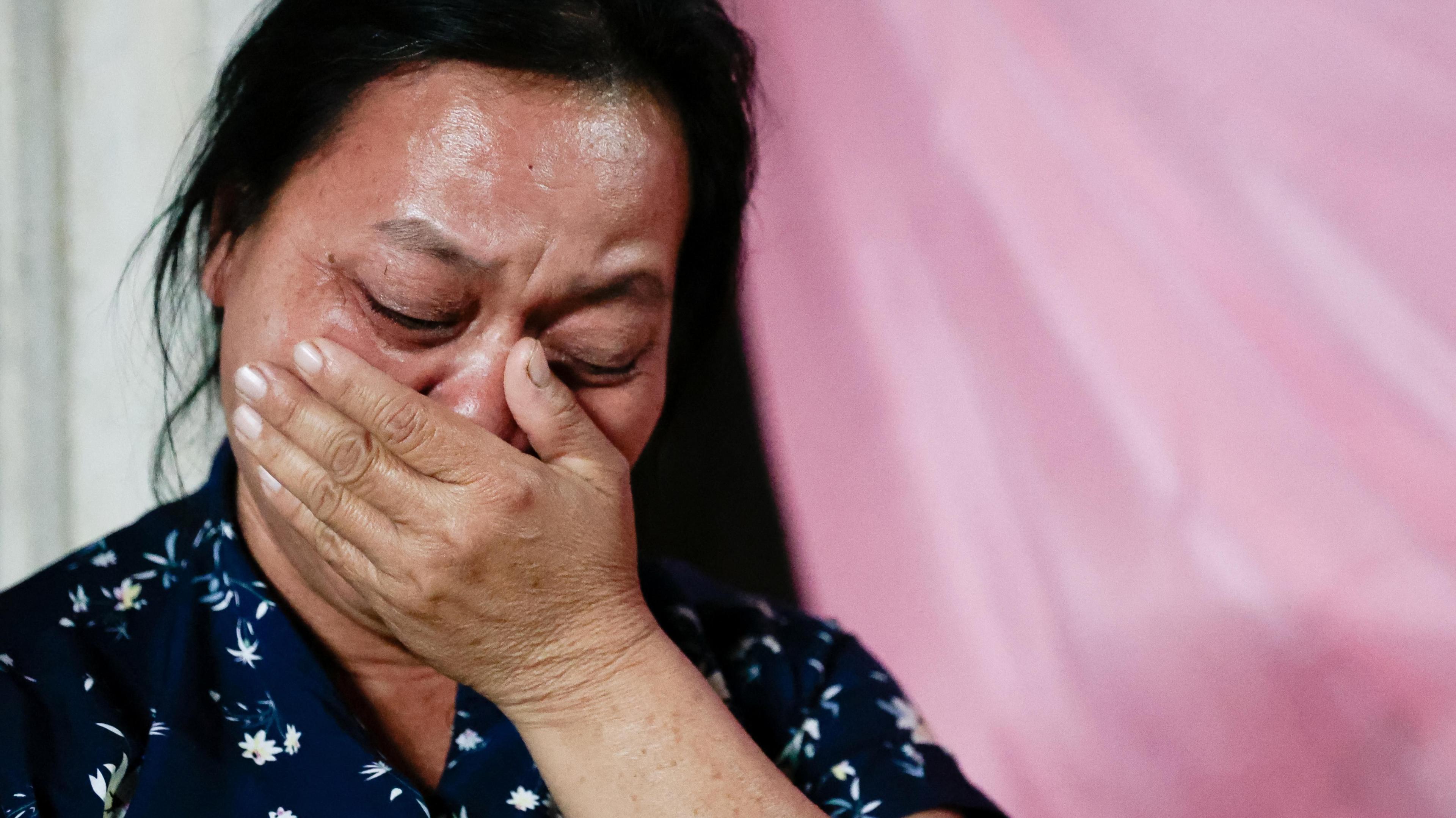 Wiwwaew Sriaoun, 53, mother of Thai hostage Watchara Sriaoun who was captured during the deadly October 7, 2023 attack by Hamas, holds her hand to her mouth, her eyes closed as as she weeps. She is wearing a dark blue blouse and stands against a pink background