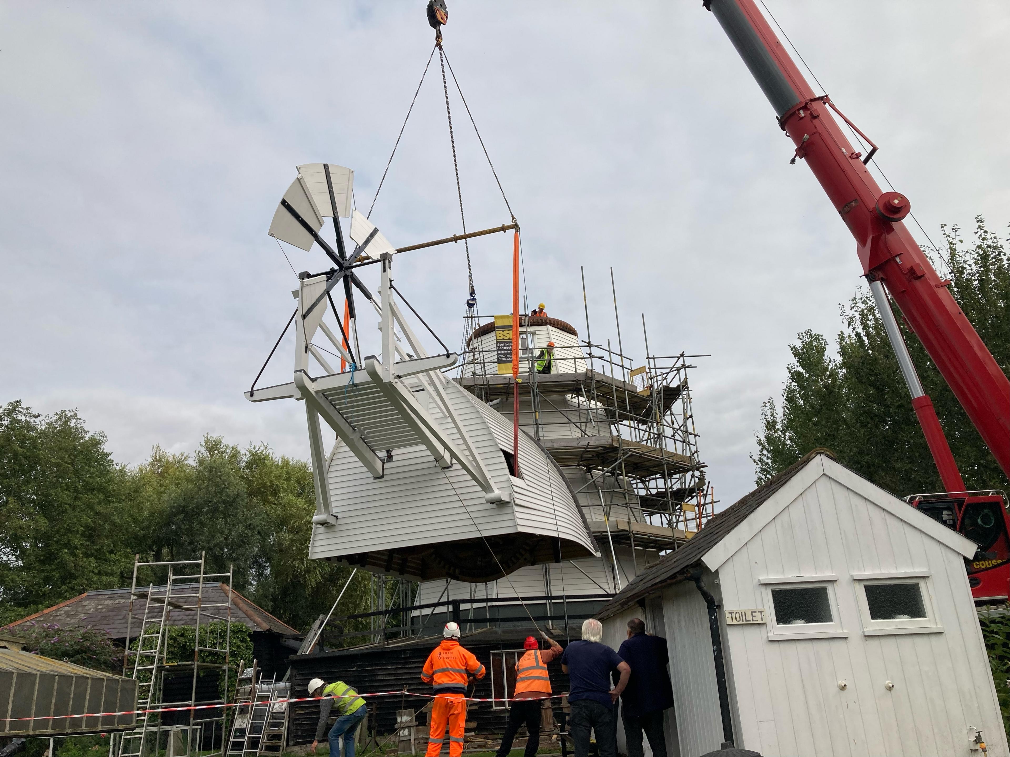 A crane lifts the 18th Century windmill cap into position