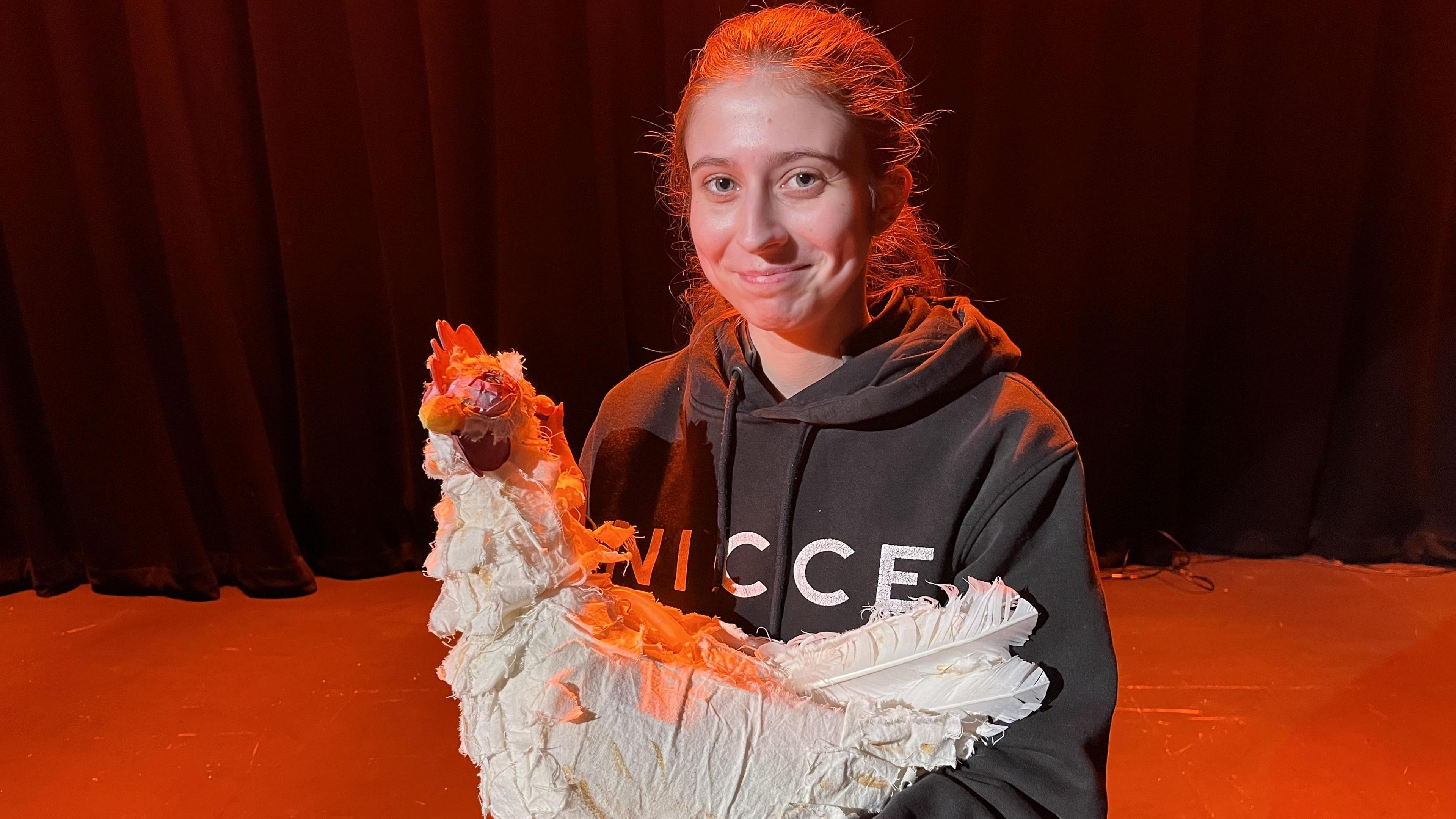 Sarah Humphrey holding a puppet chicken on stage