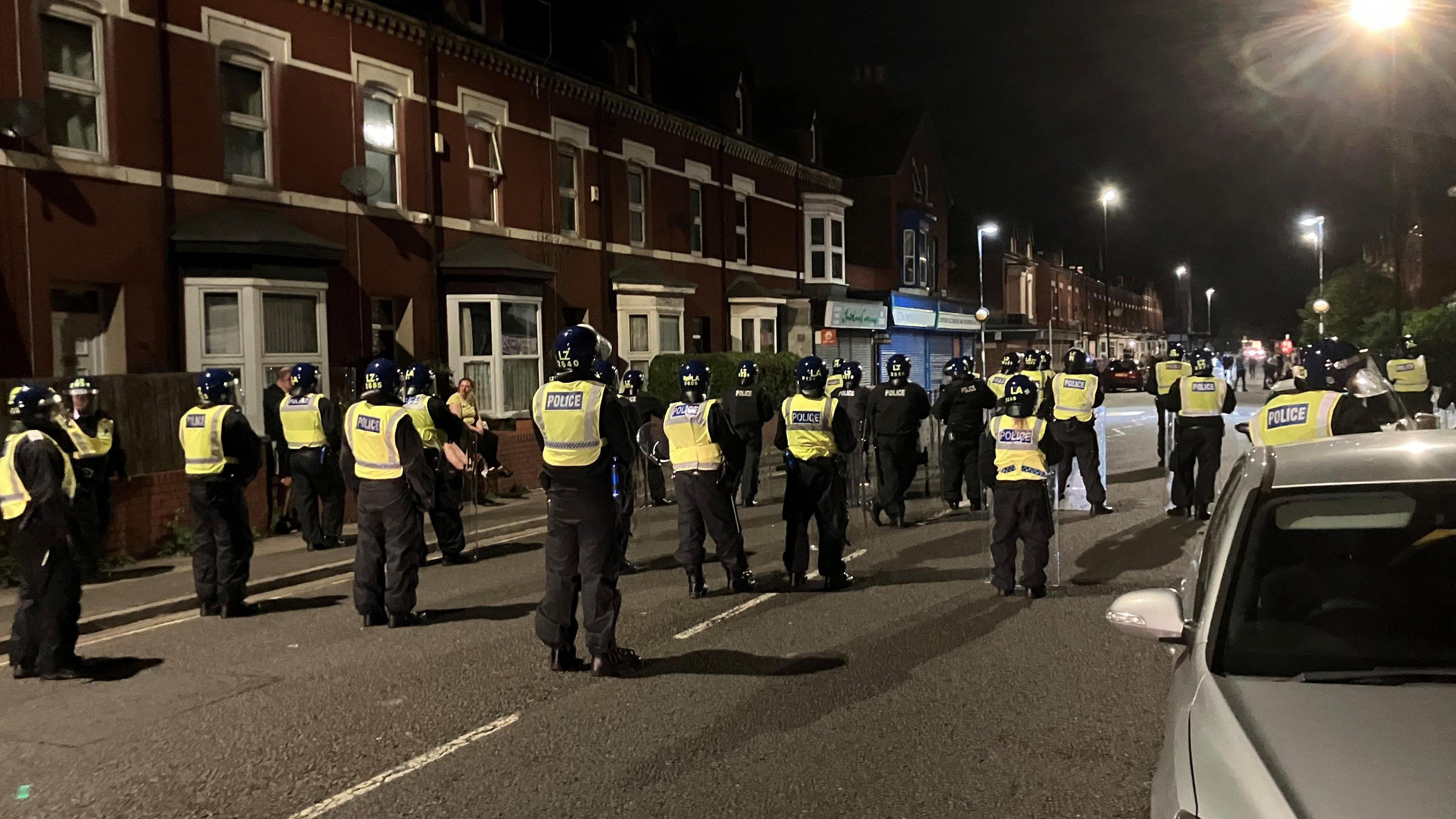 Police officers wearing riot gear and with shields stand on a street in Hartlepool