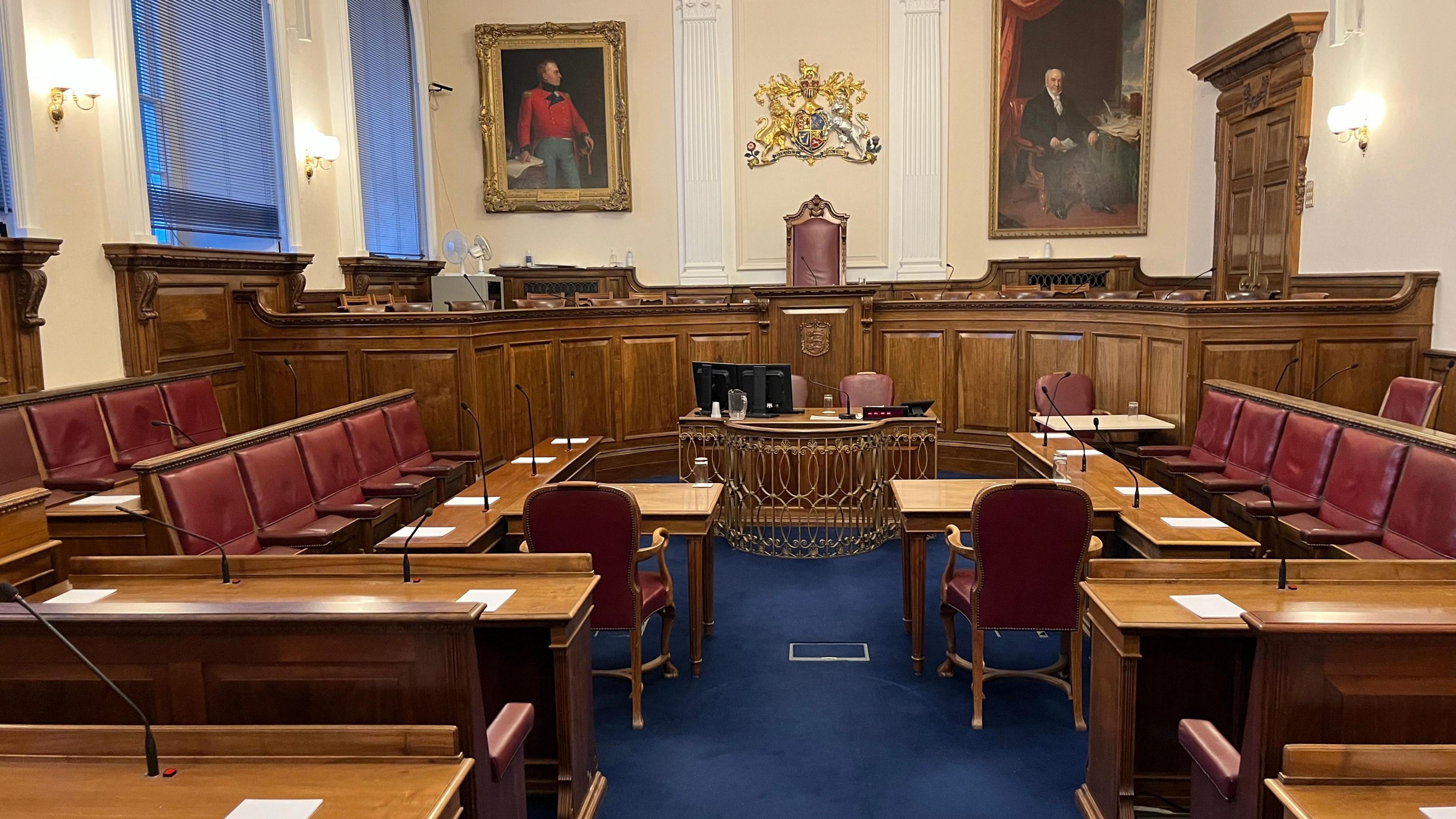 Guernsey's Royal Court with burgundy chairs and brown desks in a courtroom set-up. 