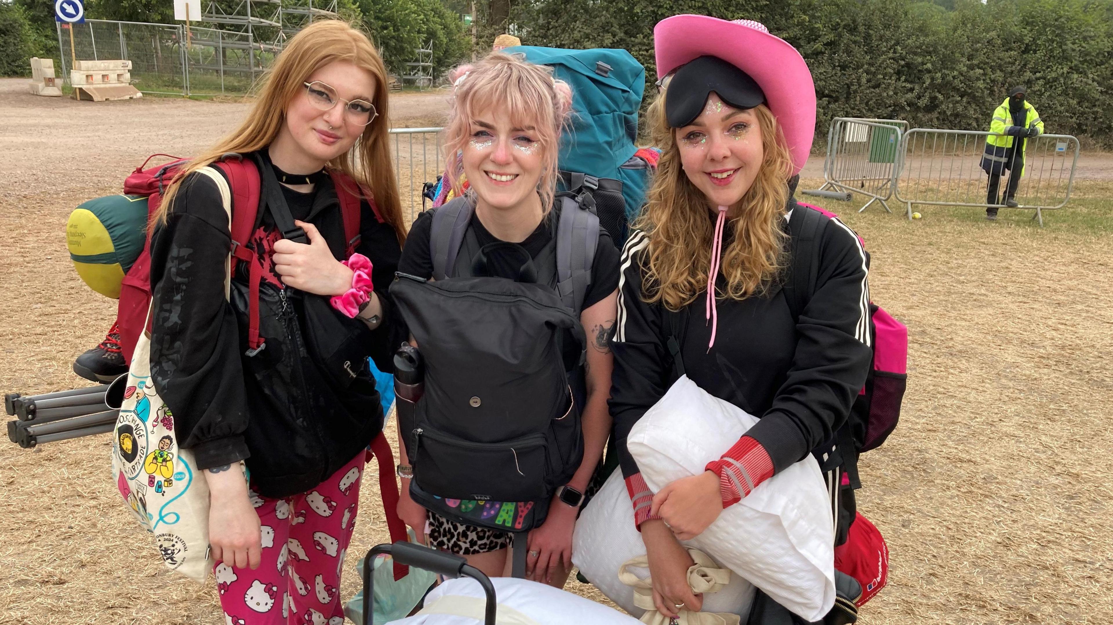 Three women stood next to each other with lots of luggage