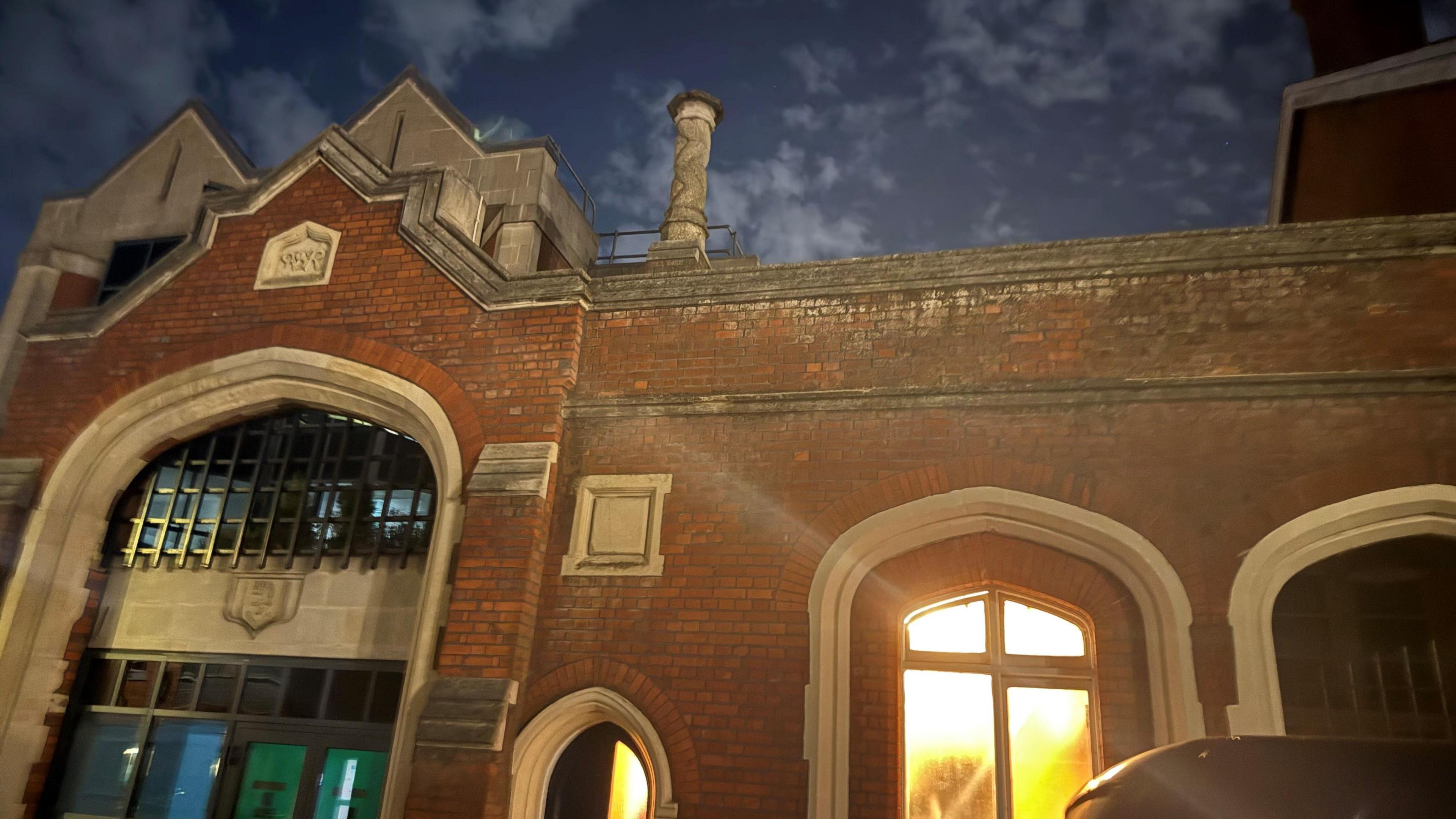 The front of Windsor & Eton Riverside Station at night. Light is coming through one of the windows.