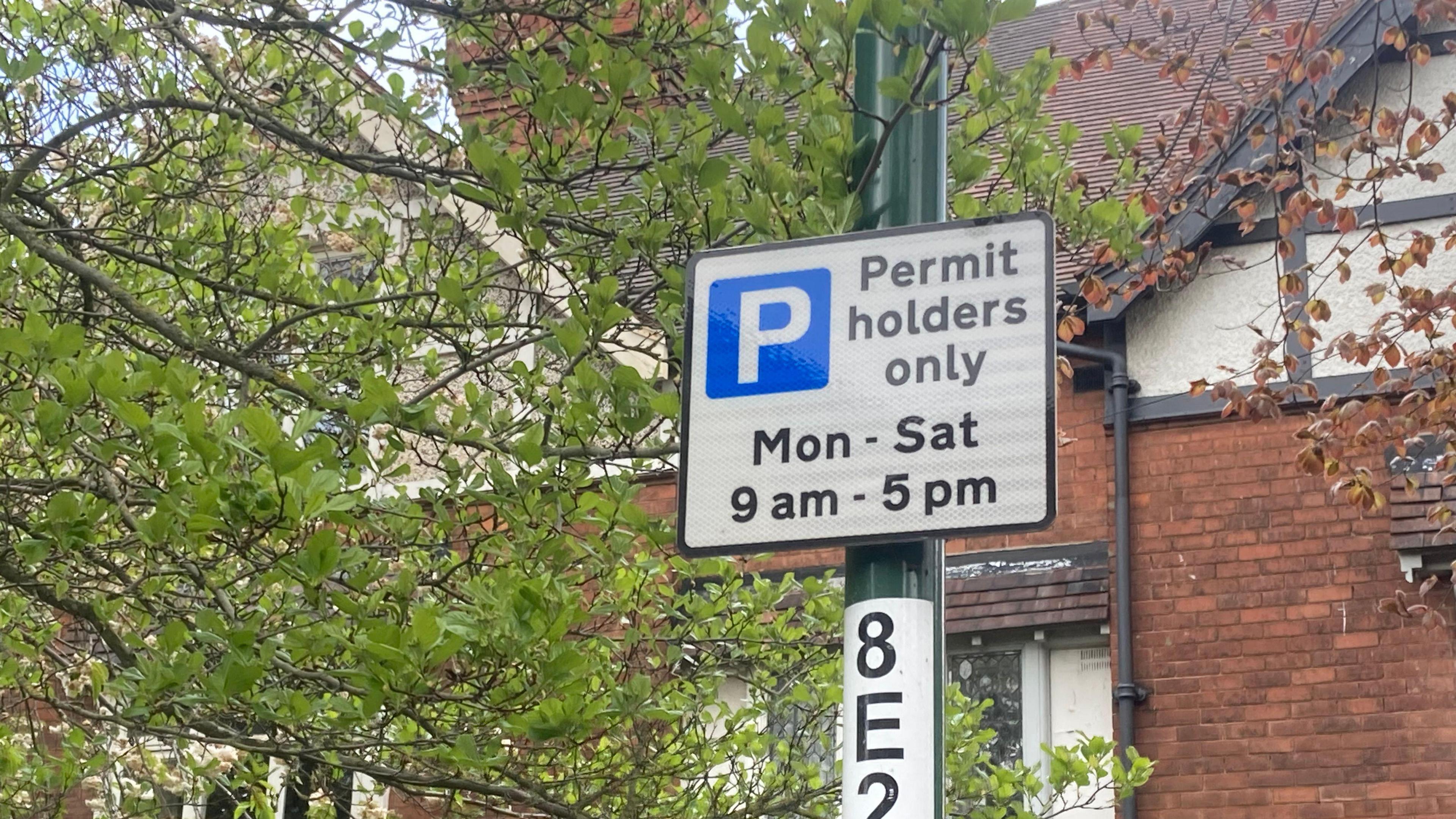 A parking sign on a lamp post reading "Permit holders only" 