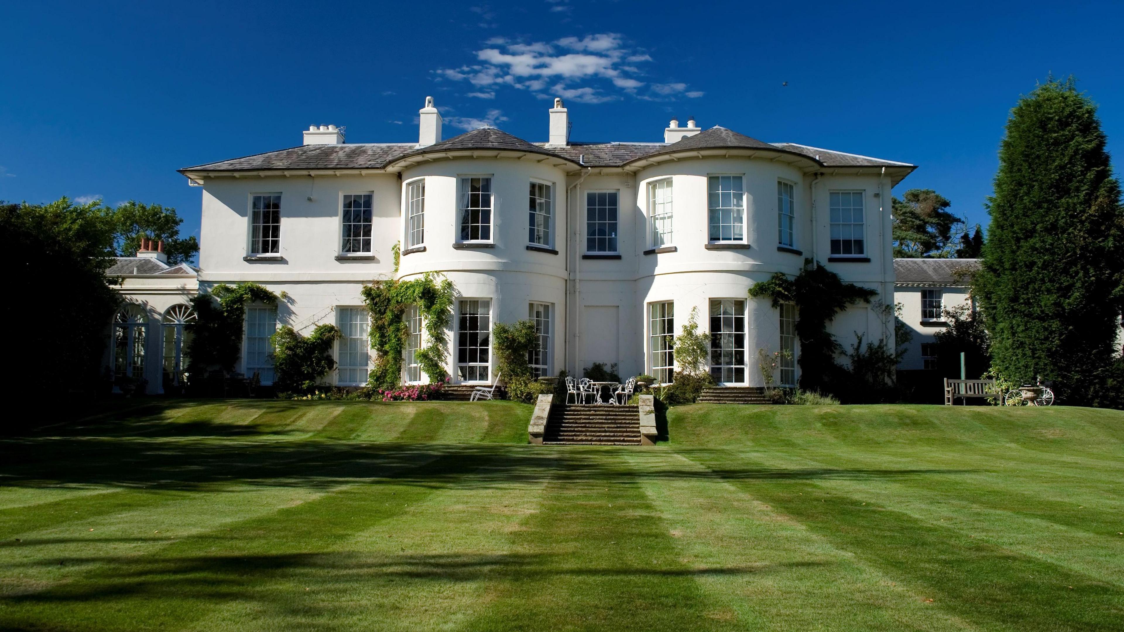 A large white house behind a lawn of freshly cut grass