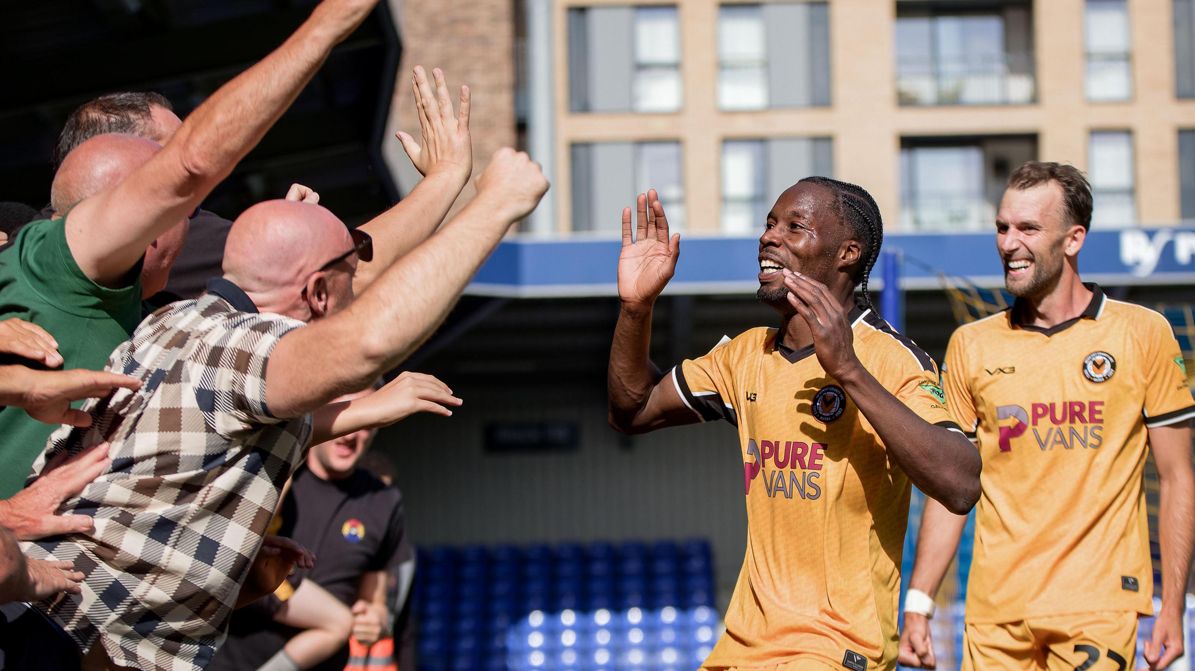 Newport County's Yahya Bamba celebrates with supporters after scoring during their fixture with AFC Wimbledon