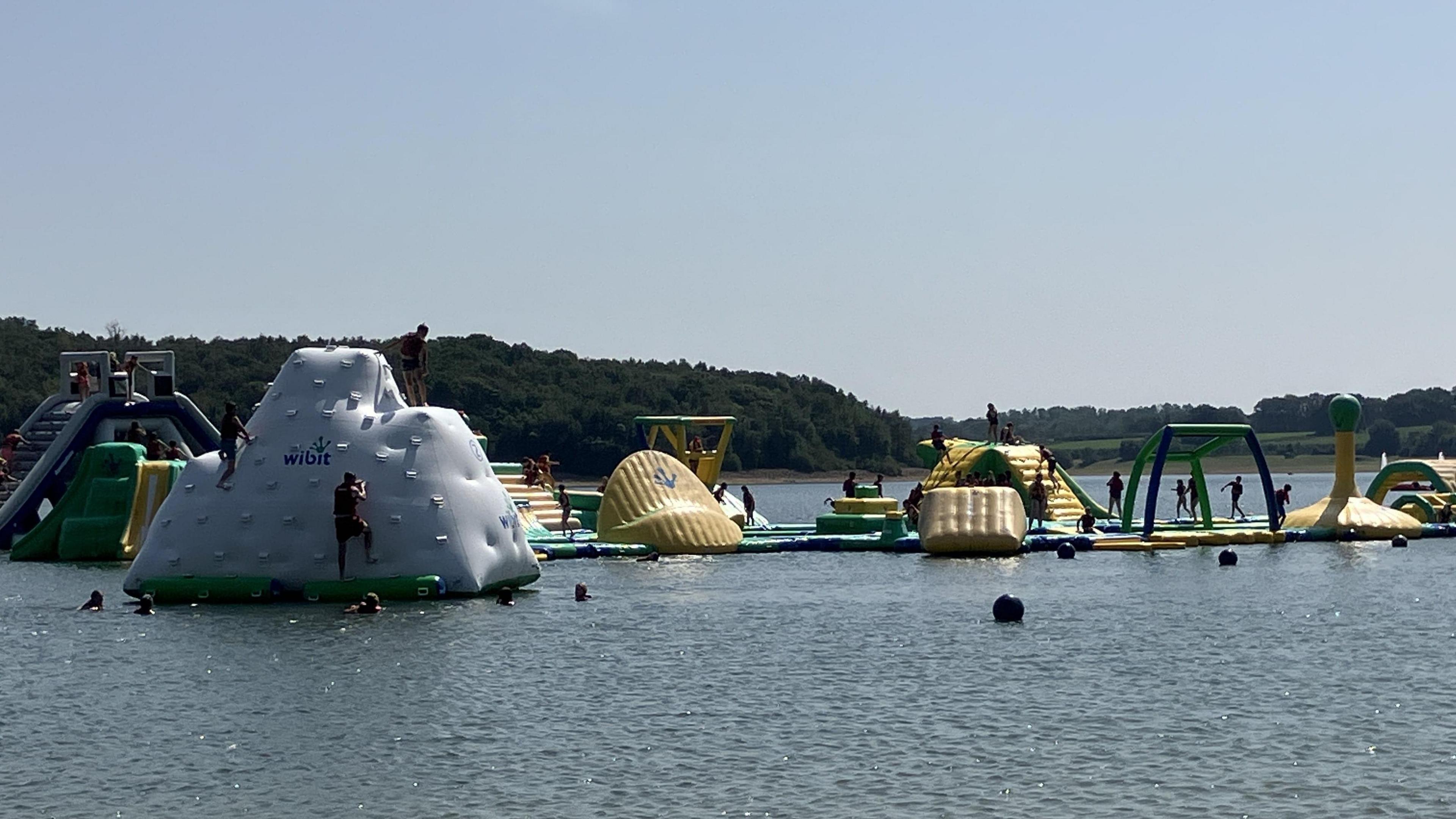 People climbing structures and inflatable obstacles at water park at Bewl Water