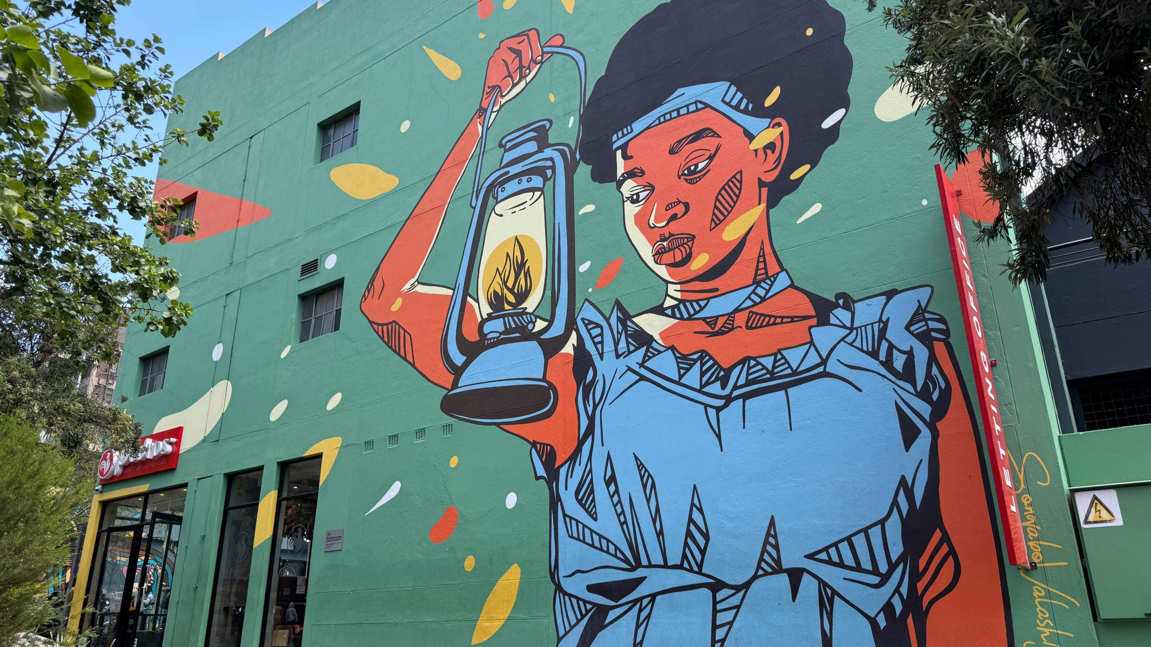 A mural of a lady wearing a blue dress holding a lantern