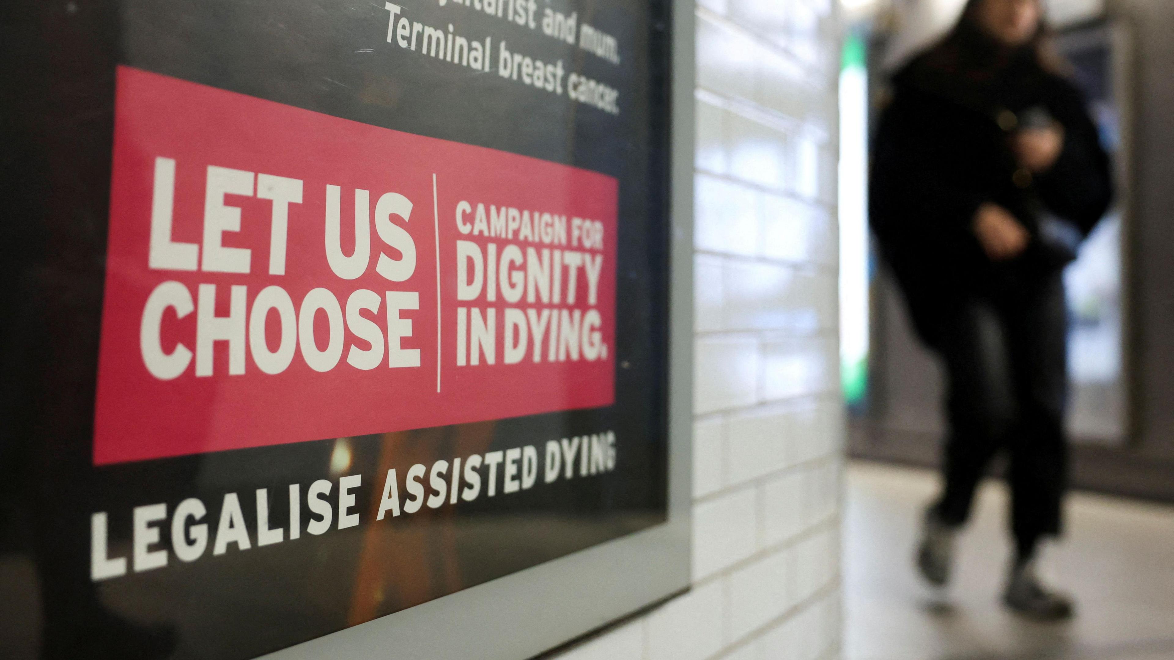 A London underground passenger walks past an assisted dying rights billboard.