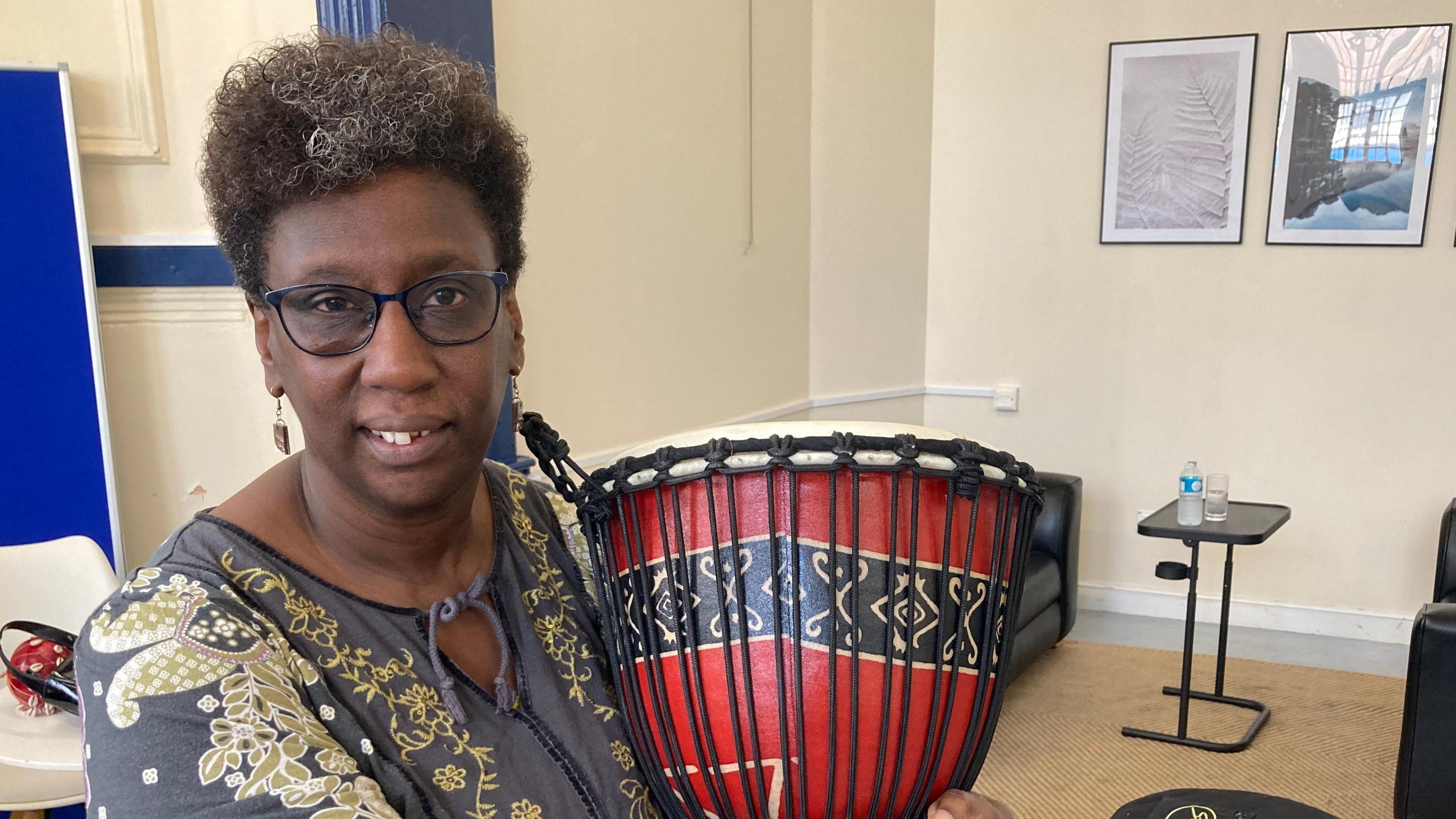 Drumming instructor holding a red djembe drum