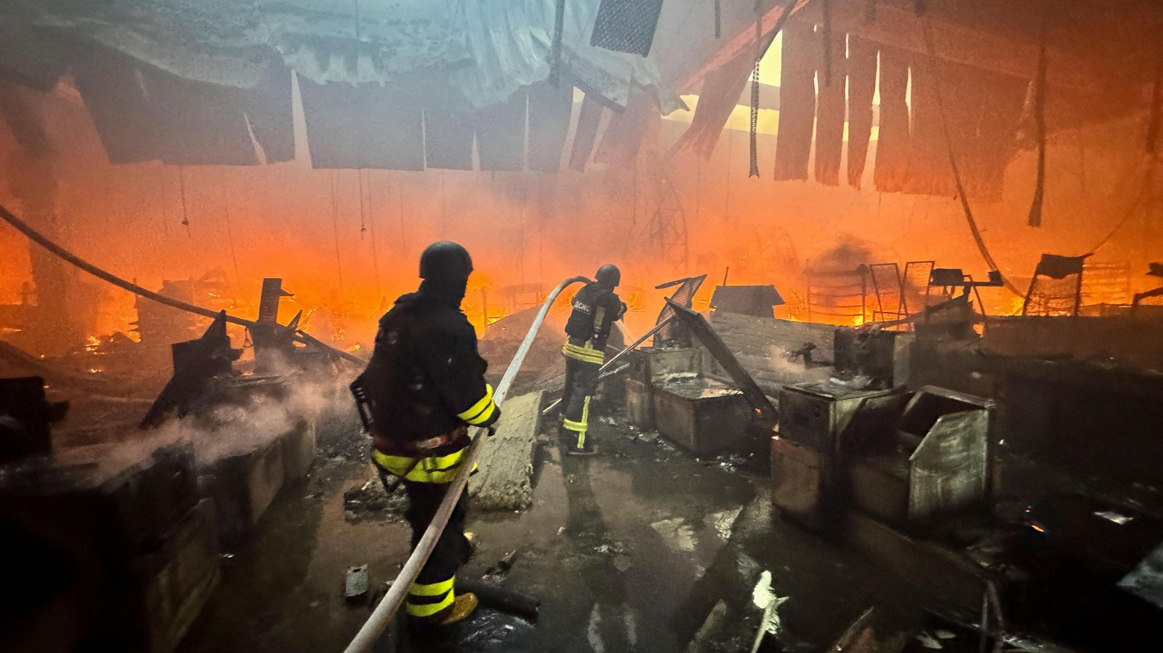 Firefighters work at a site of a household item shopping mall hit by a Russian air strike, amid Russia's attack on Ukraine, in Kharkiv, Ukraine