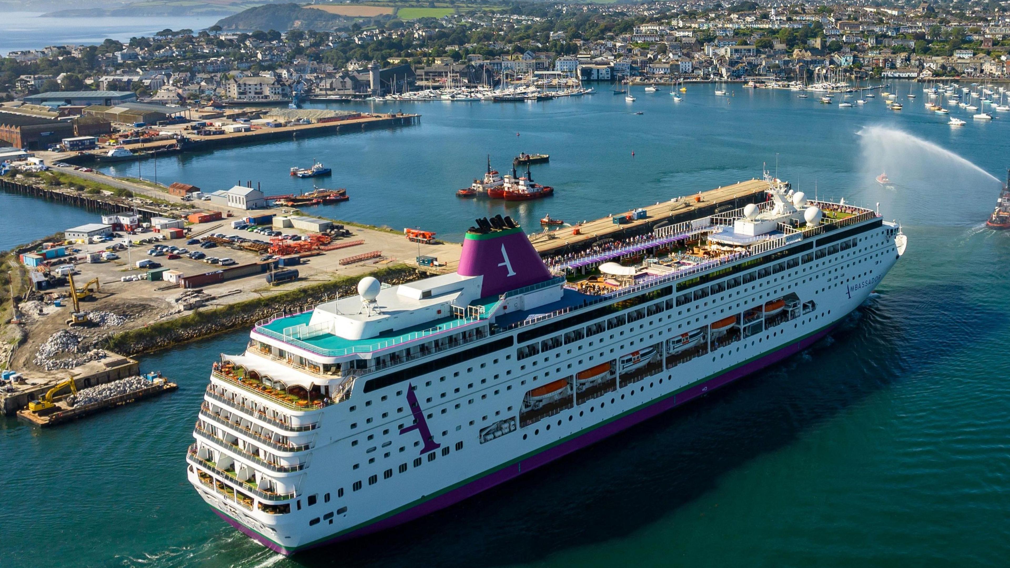 A cruise ship sailing into Falmouth Harbour with the town in the distance 
