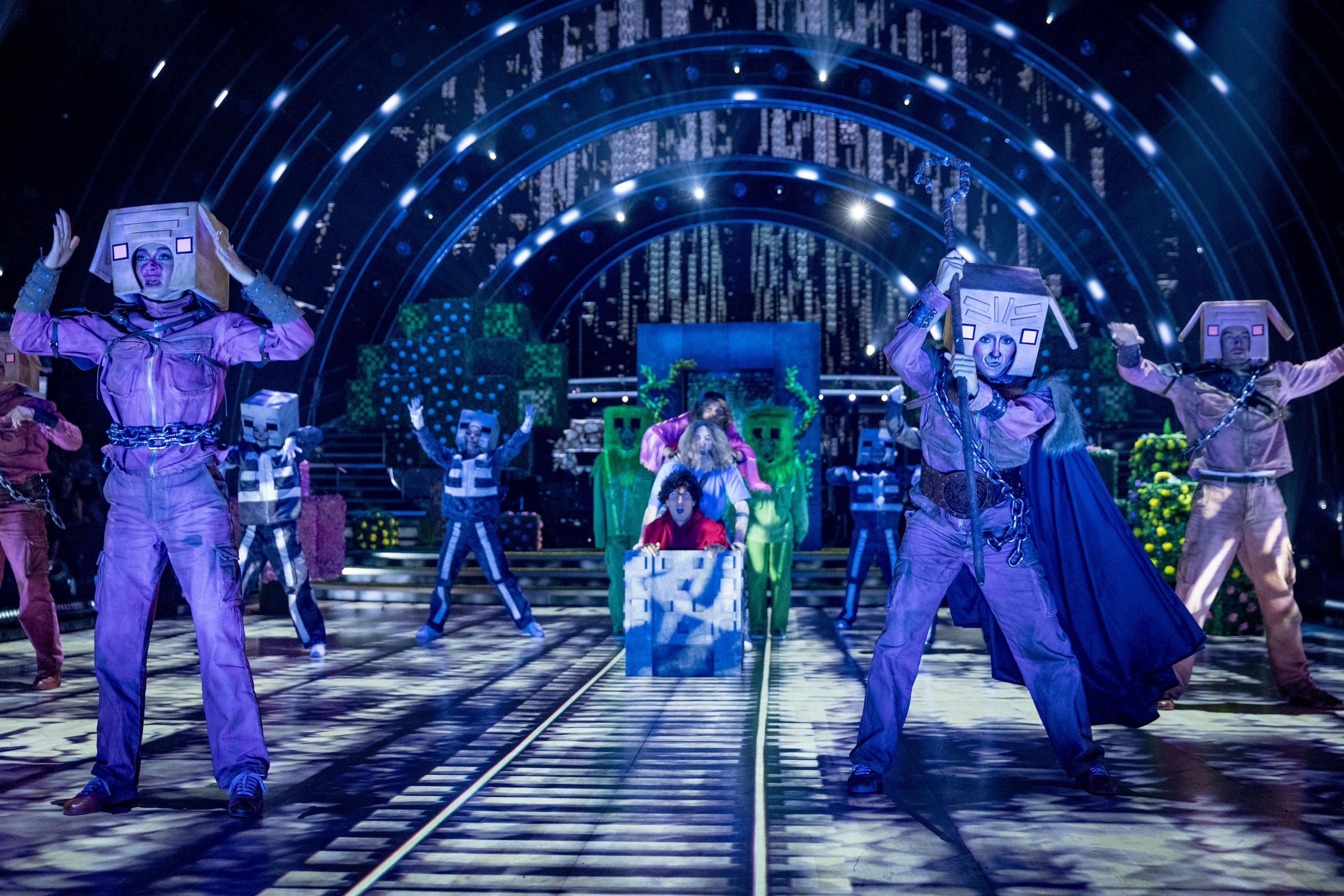 strictly professionals in a spooky blue light dressed up ass characters from the Minecraft movie - some are in a carriage on a train track being pushed