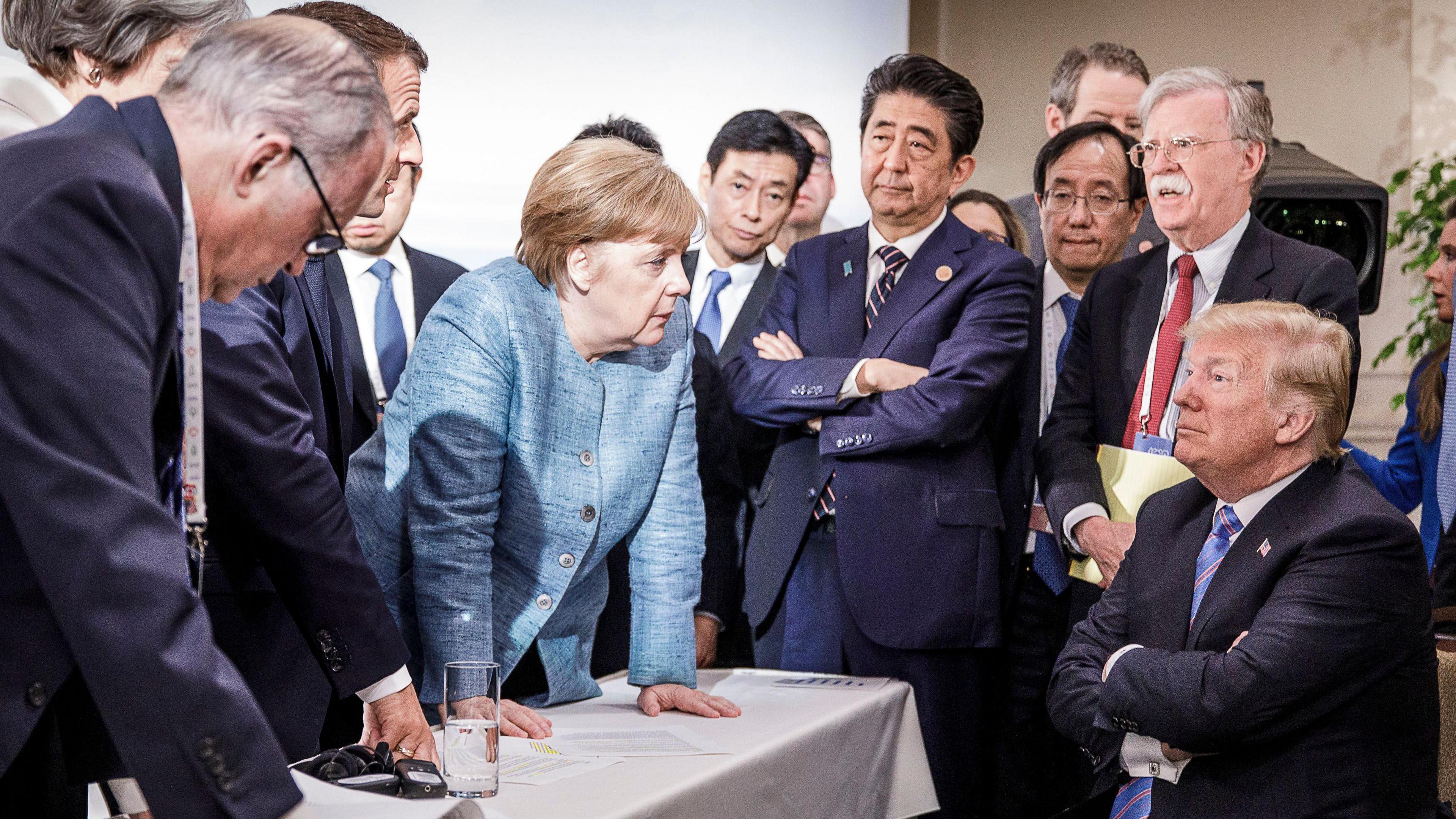 Angela Merkel stares down a seated Donald Trump as a crowd of world leaders looks on, in an iconic image from the G7 Summit in Canada in 2018