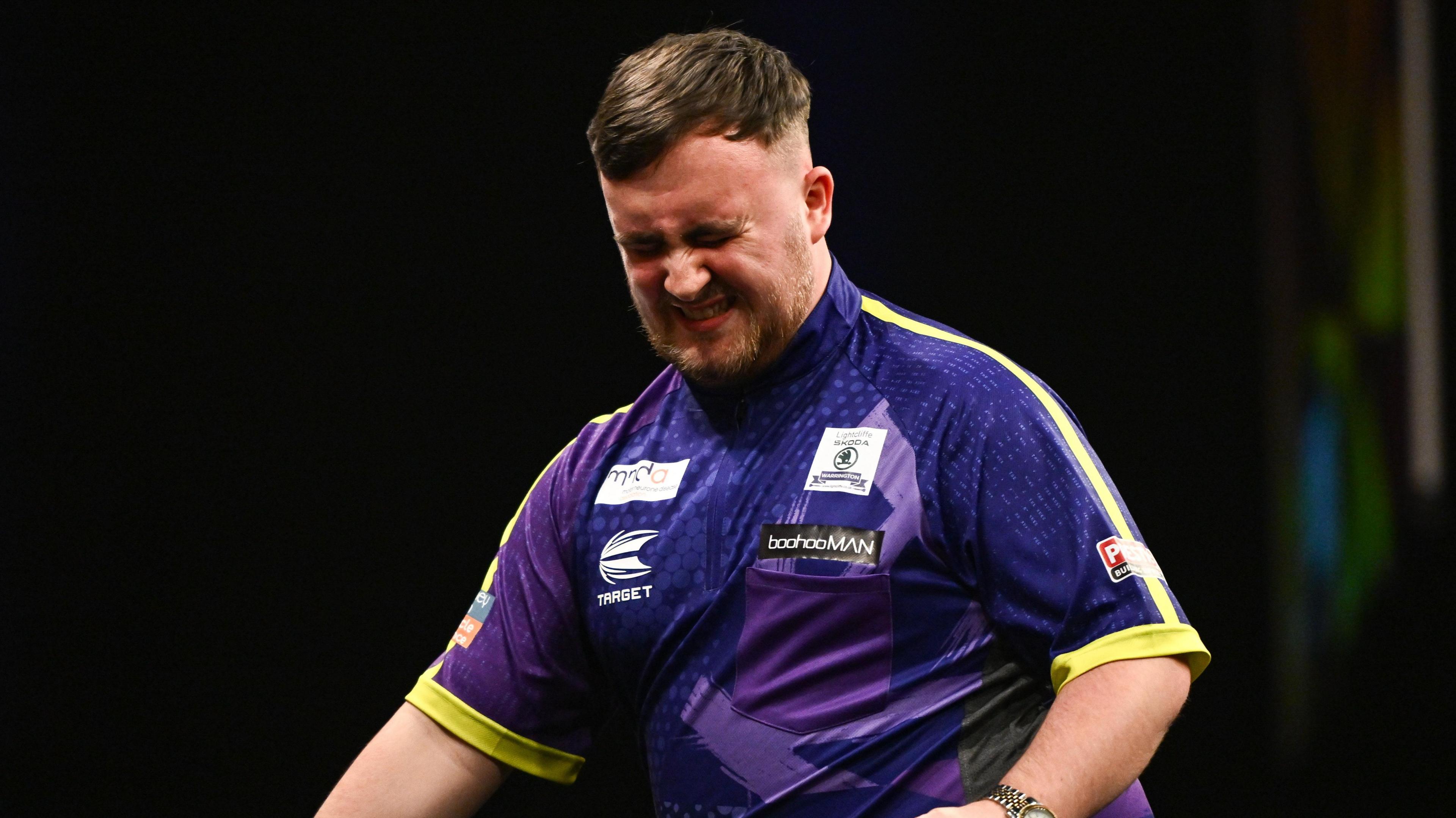 Luke Littler grimaces after suffering a defeat