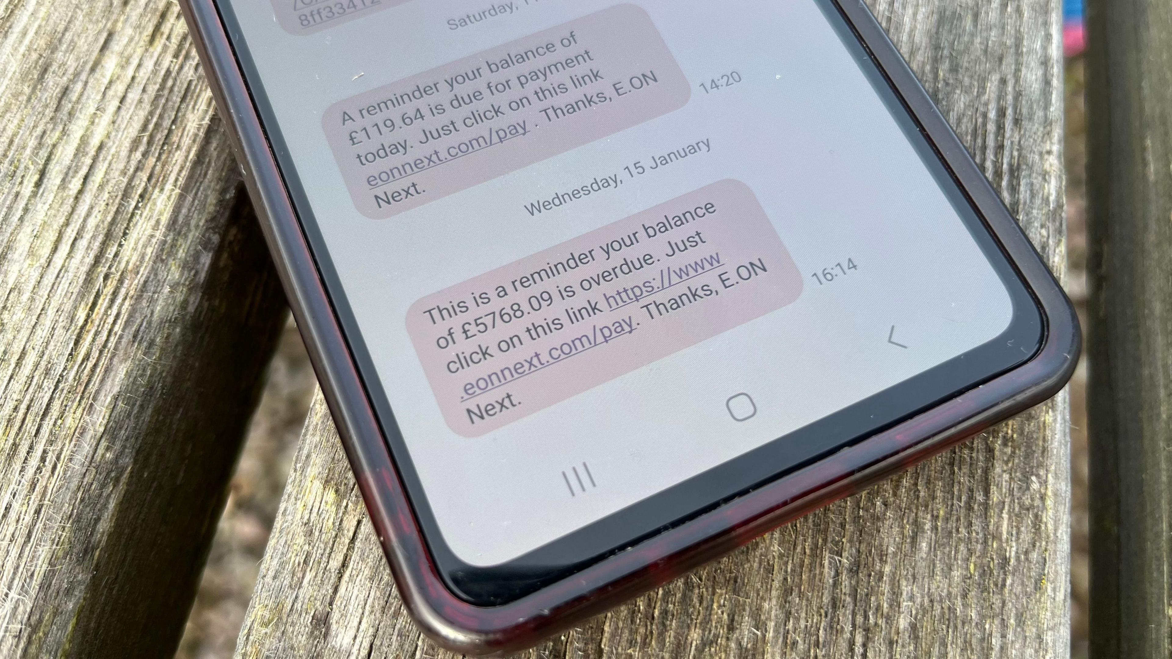 A photo of a phone displaying a text message bill from EON Next for £5768.09