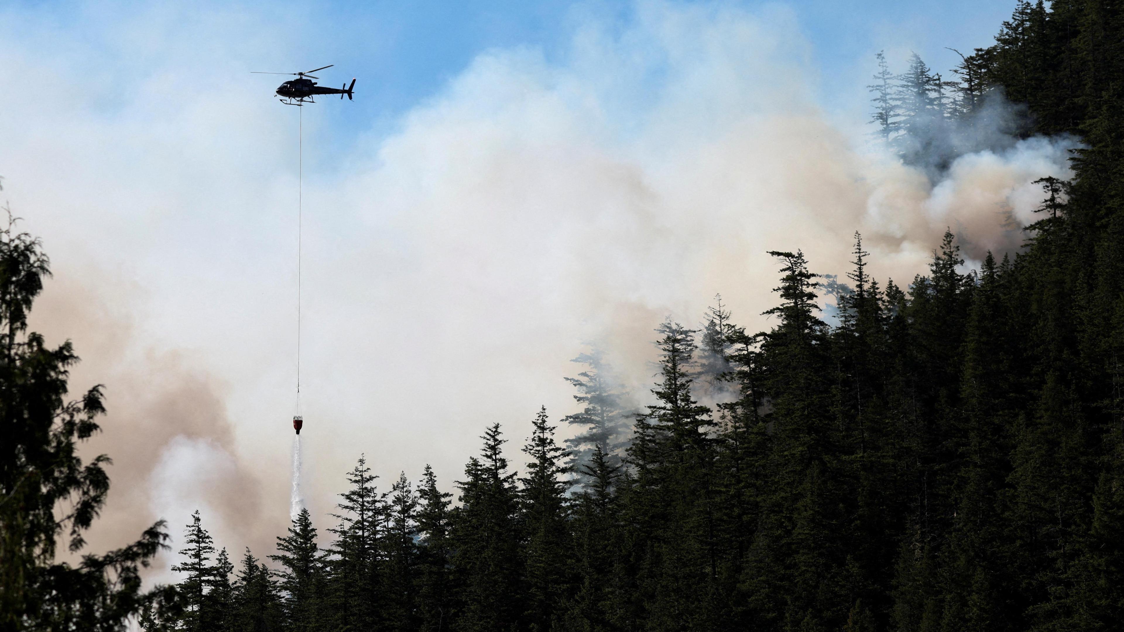 A helicopter drops water on a wildfire in Canada.