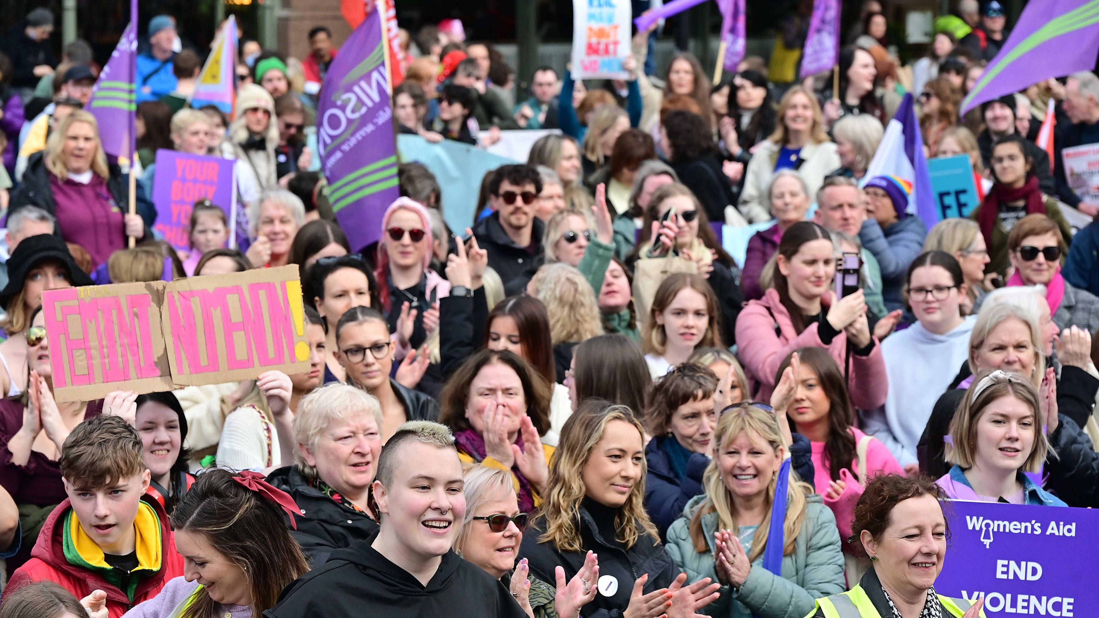 A large crowd is pictured attending a march on International Women's Day in Belfast and some of the crowd are holding placards