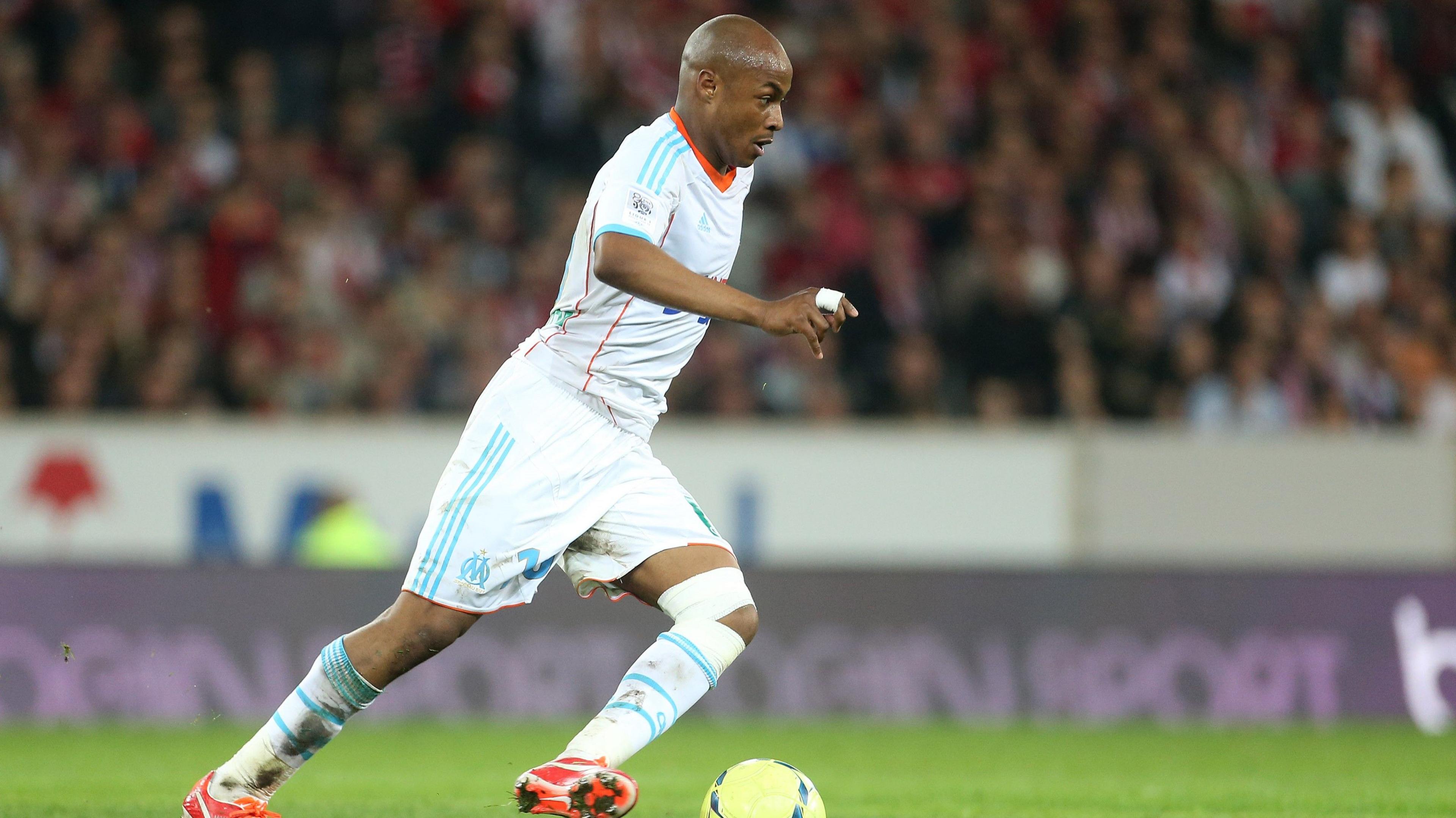 Andre Ayew wears and all-white kit with light blue trim as he dribbles a football while playing for Marseille in 2013