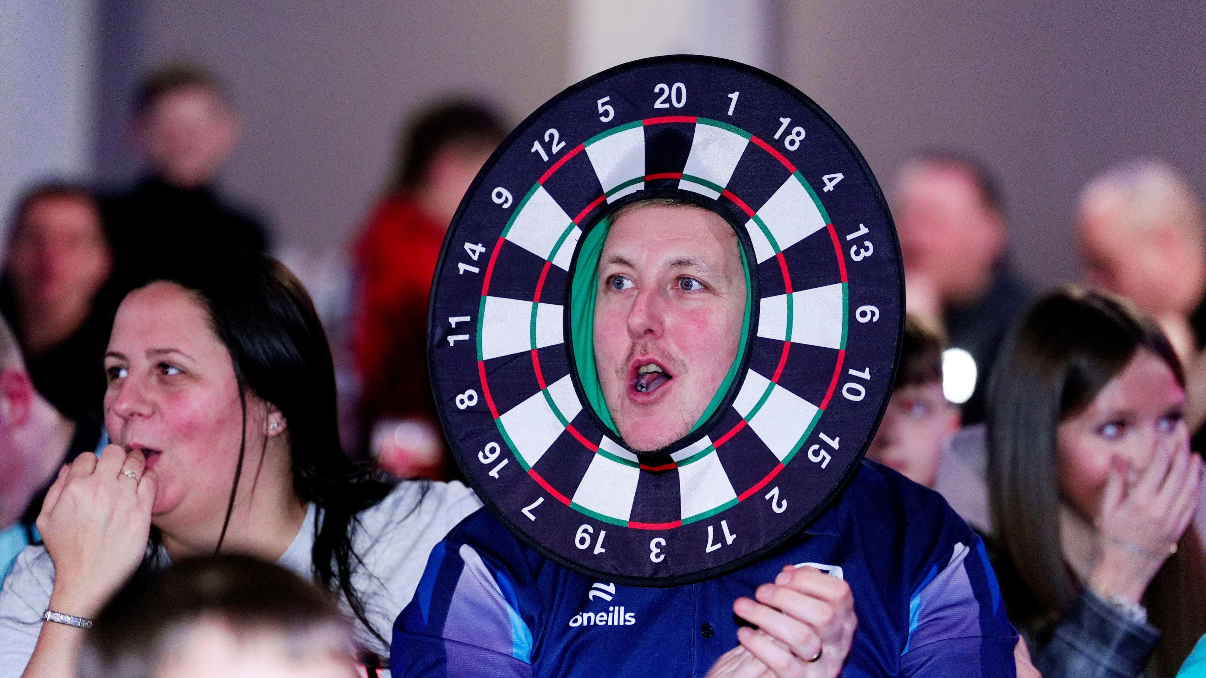 Man wearing a dart board costume clapping