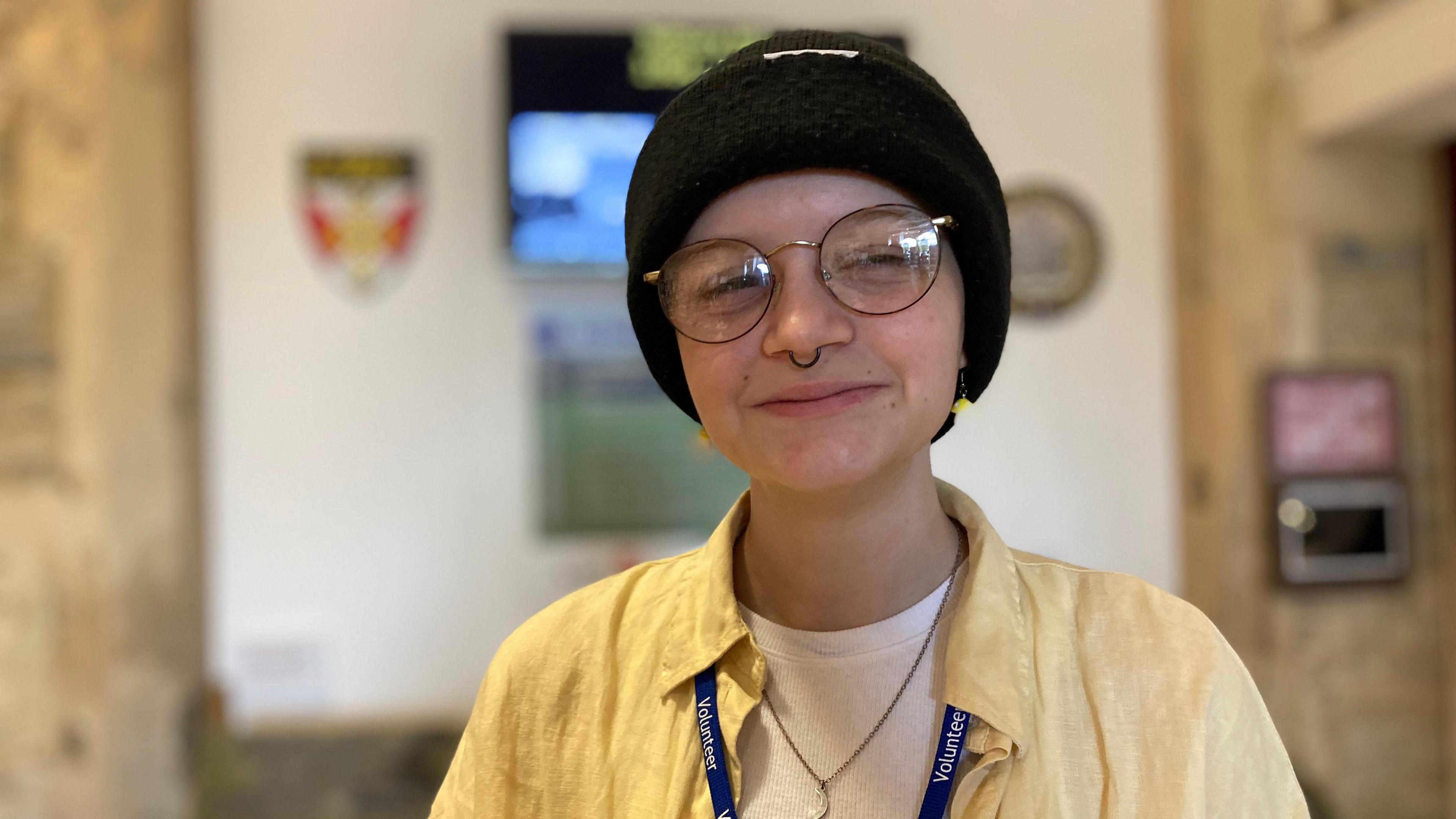 Frankie in the museum wearing a black woolly hat and yellow shirt