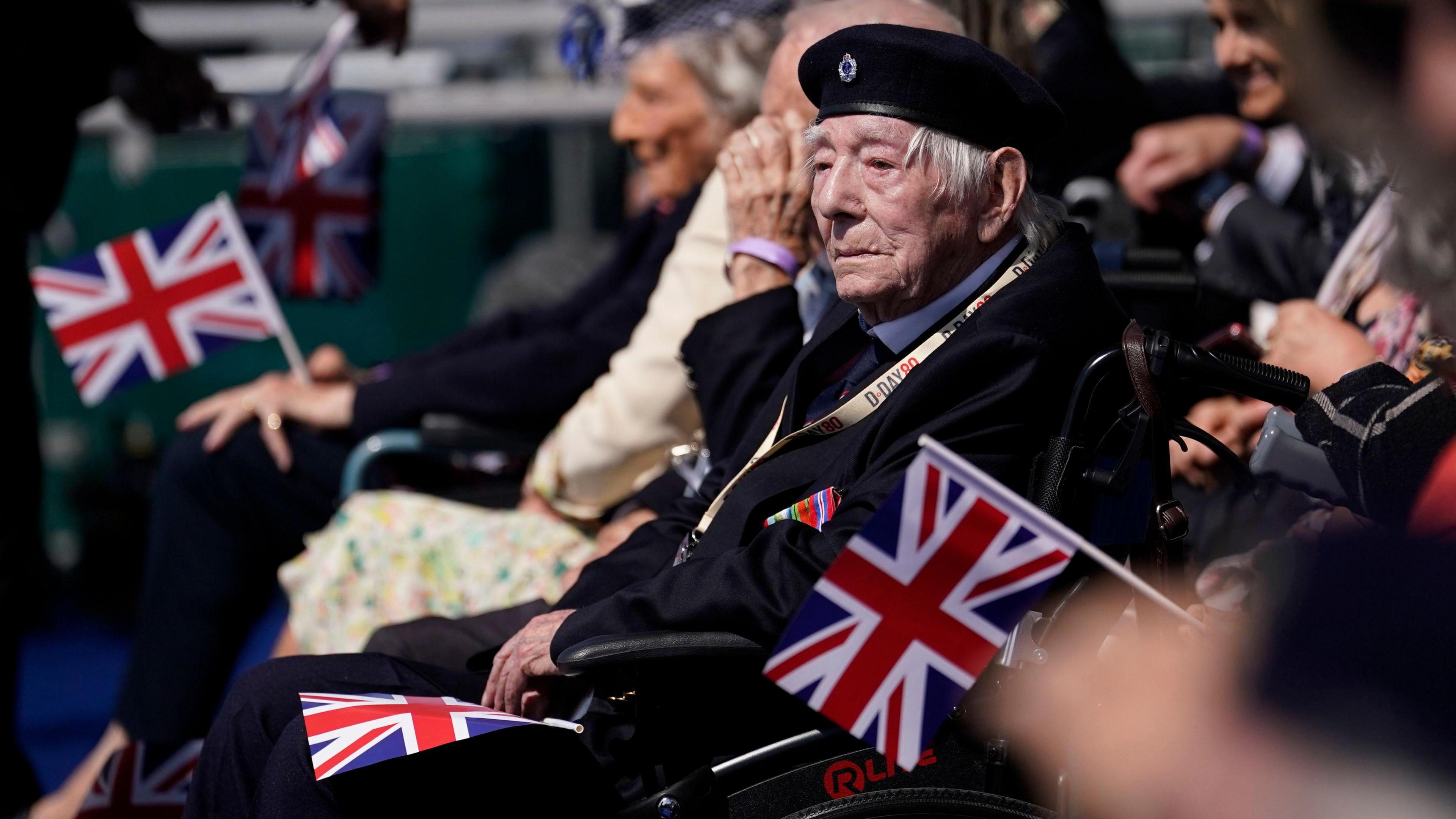 A Normandy veteran sat in a wheelchair attending the UK's national commemorative event for the 80th anniversary of D-Day