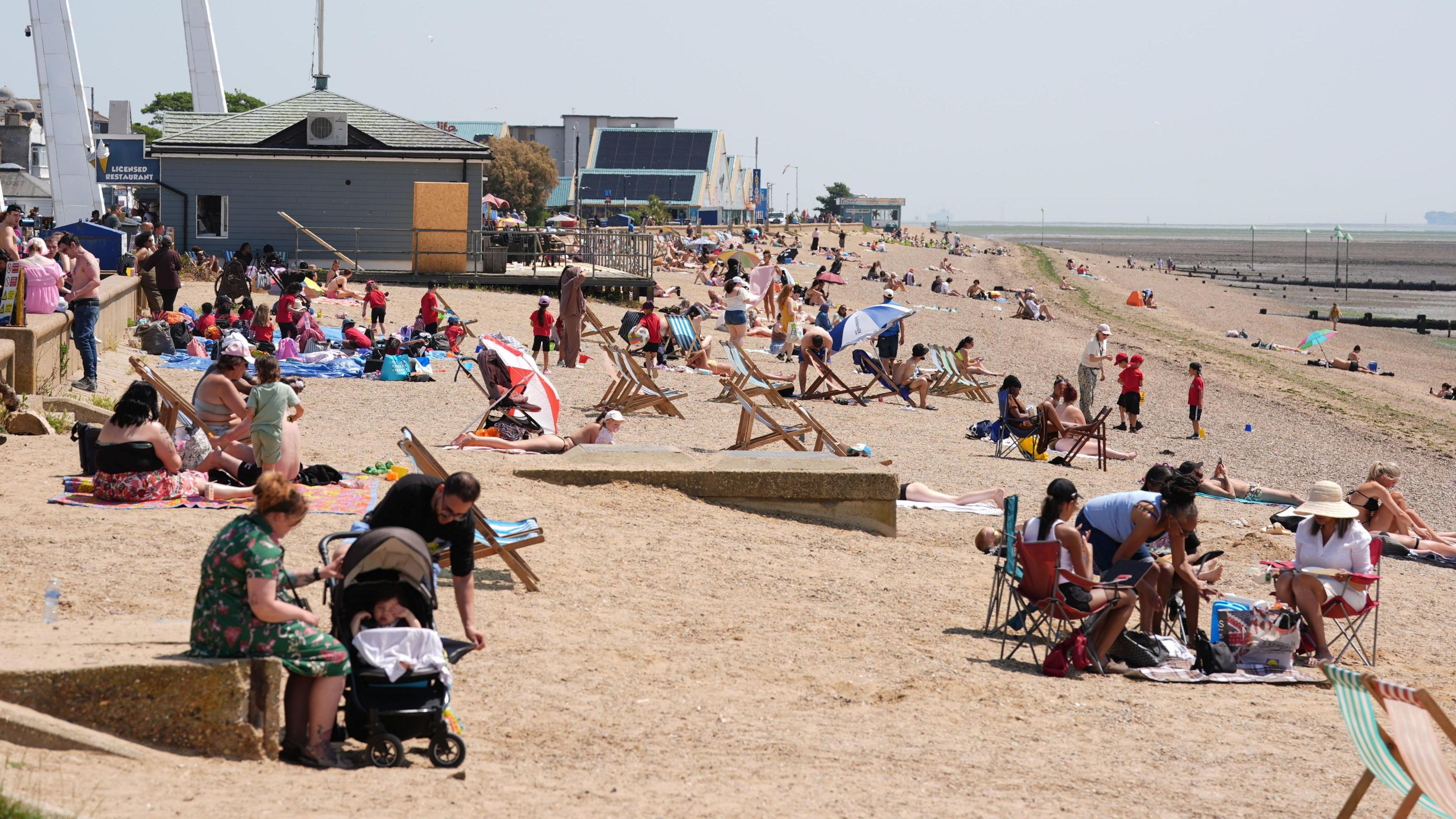 People sit on the beach in the sun.