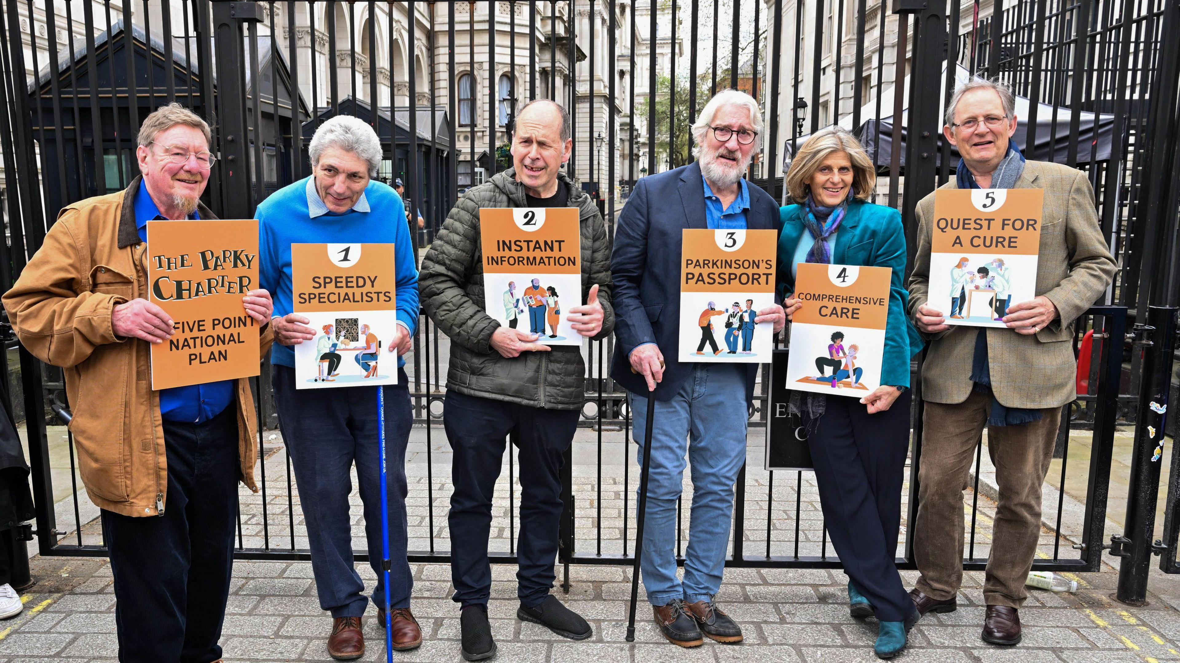 Hosts of The Movers and Shakers podcast (left-right) Mark Mardell, Paul Mayhew-Archer, Rory Cellan-Jones, Jeremy Paxman, Gillian Lacey-Solymar and Sir Nicholas Mostyn, mark World Parkinson's Day by handing in their 'Parky Charter' petition to Downing Street